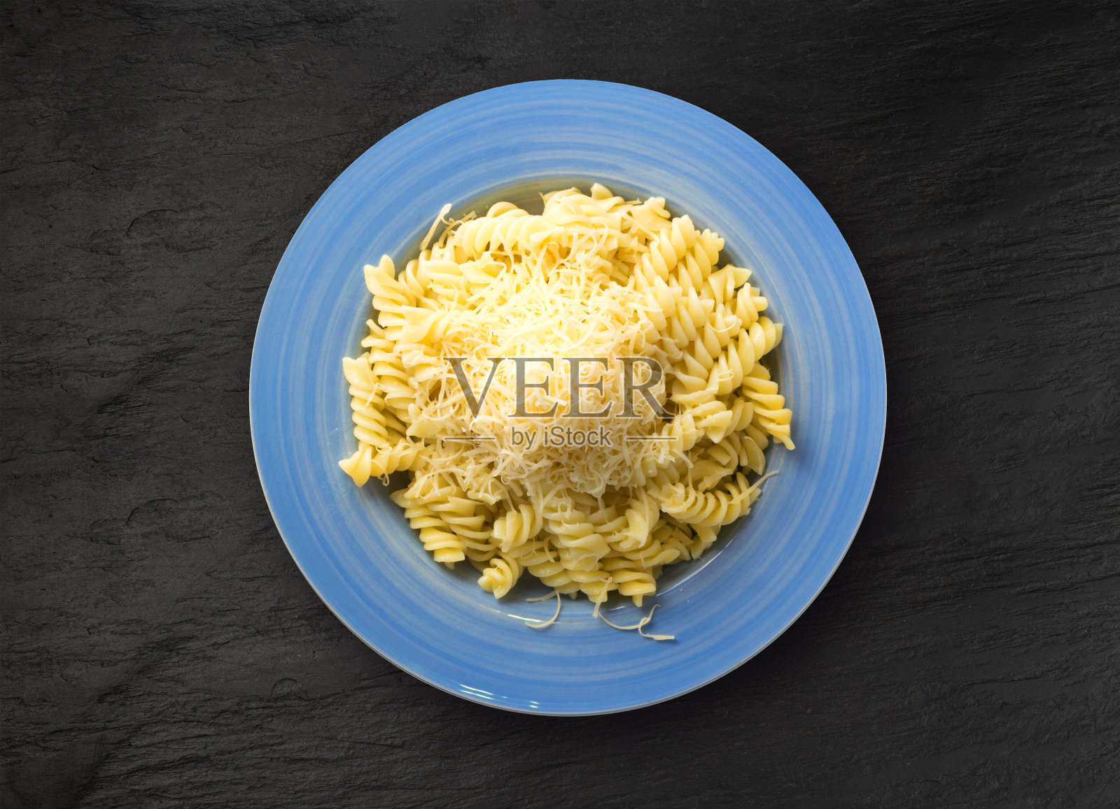 蓝盘子上的意大利面配磨碎的奶酪照片摄影图片