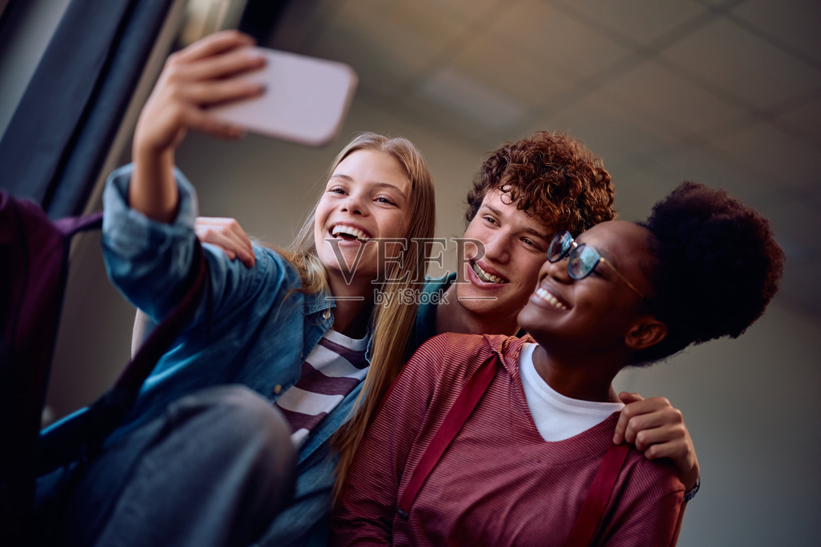 兴高采烈的学生在教室里用手机自拍。照片摄影图片