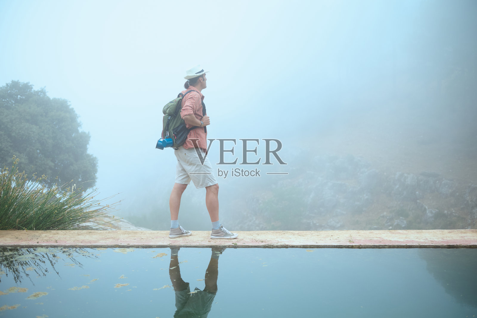 徒步旅行者站在雾蒙蒙的森林中宁静的水边，反思自然和冒险照片摄影图片