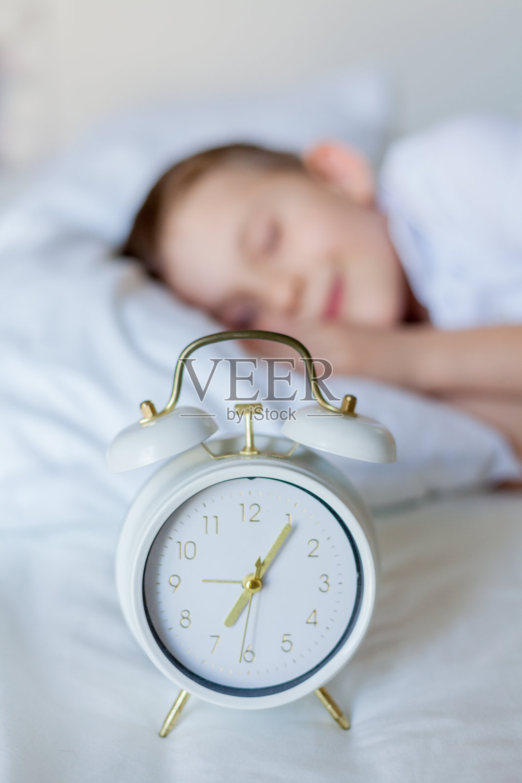 带着闹钟睡在床上的男生照片摄影图片