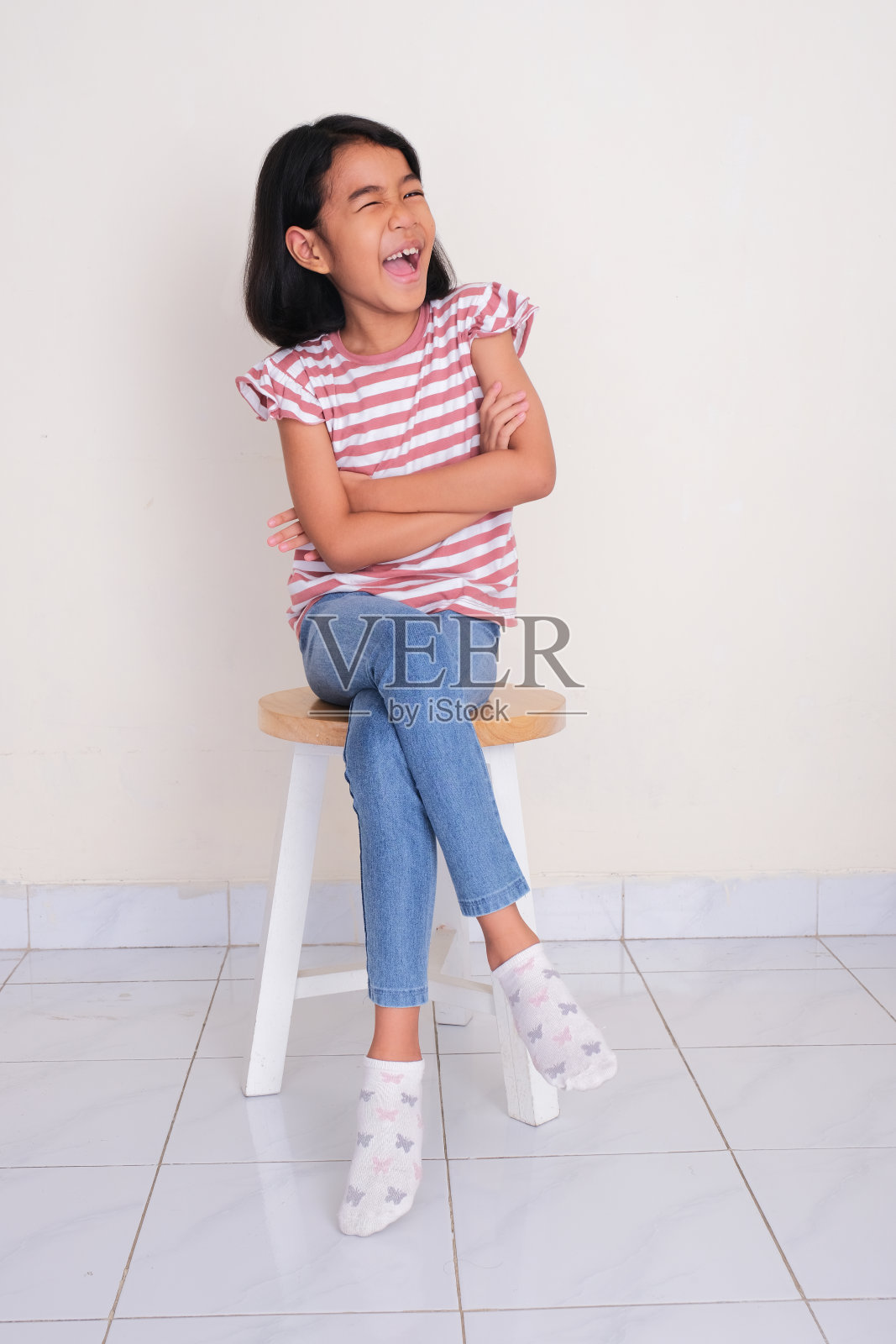 亚洲小女孩坐在椅子上，露出快乐的表情照片摄影图片