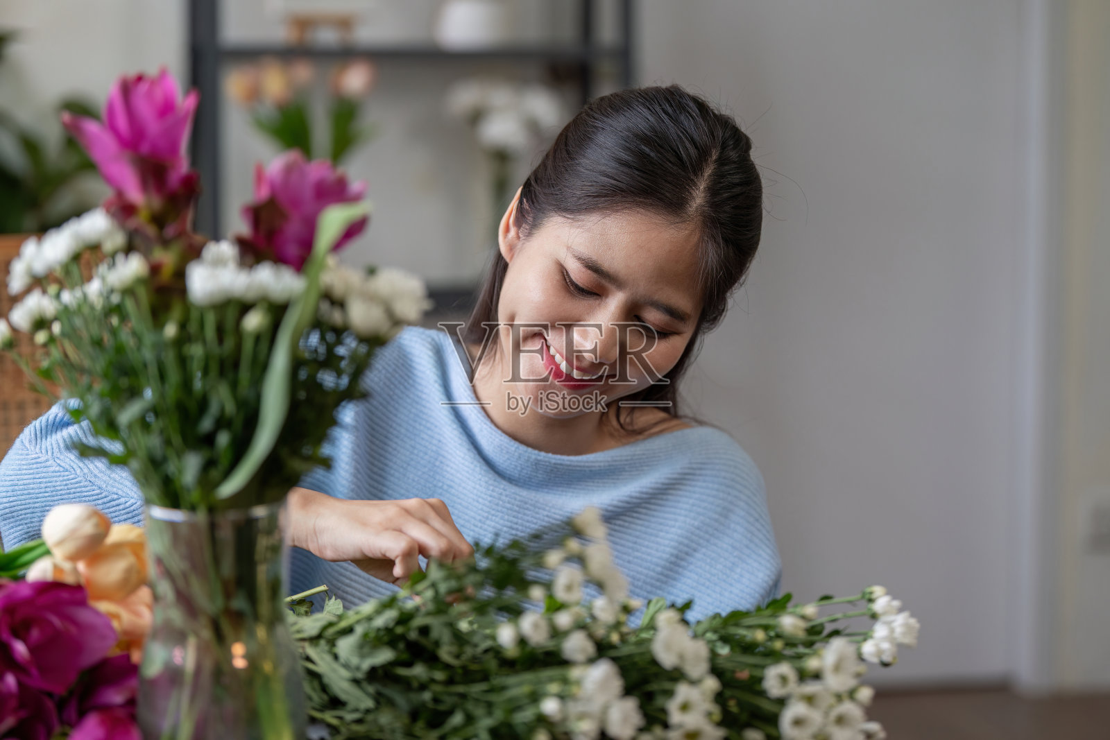女人在家里插花，微笑着享受花饰，室内生活方式照片摄影图片