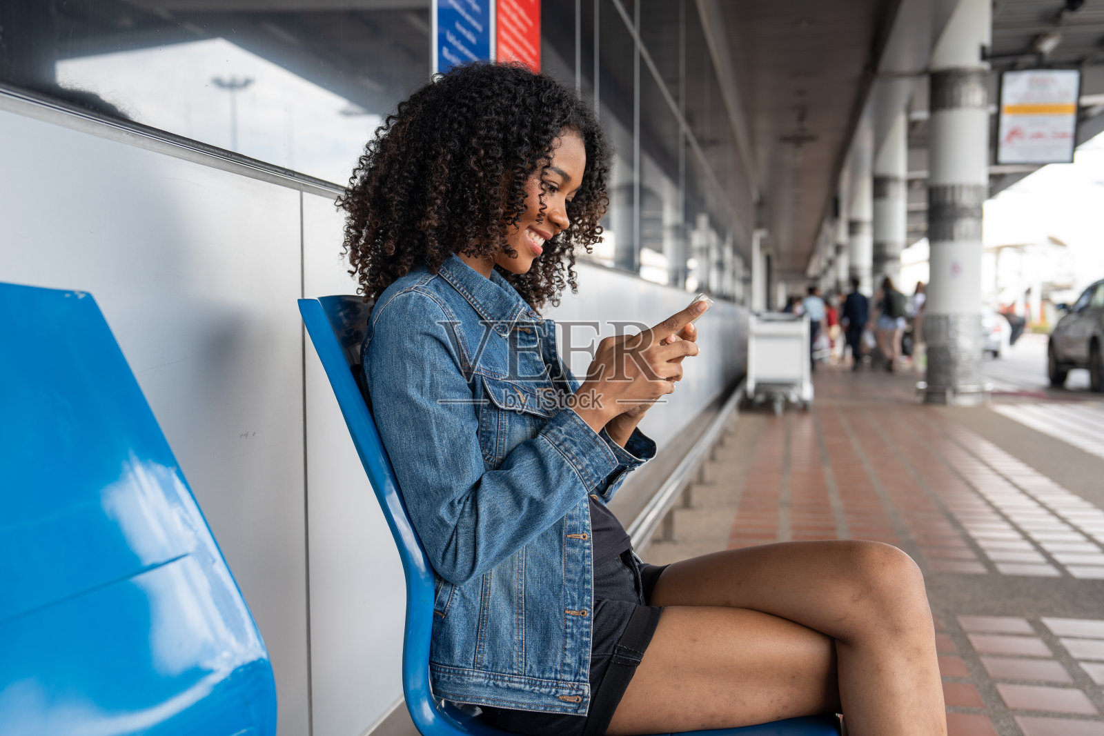 非裔美国女性在机场用智能手机给朋友发短信照片摄影图片