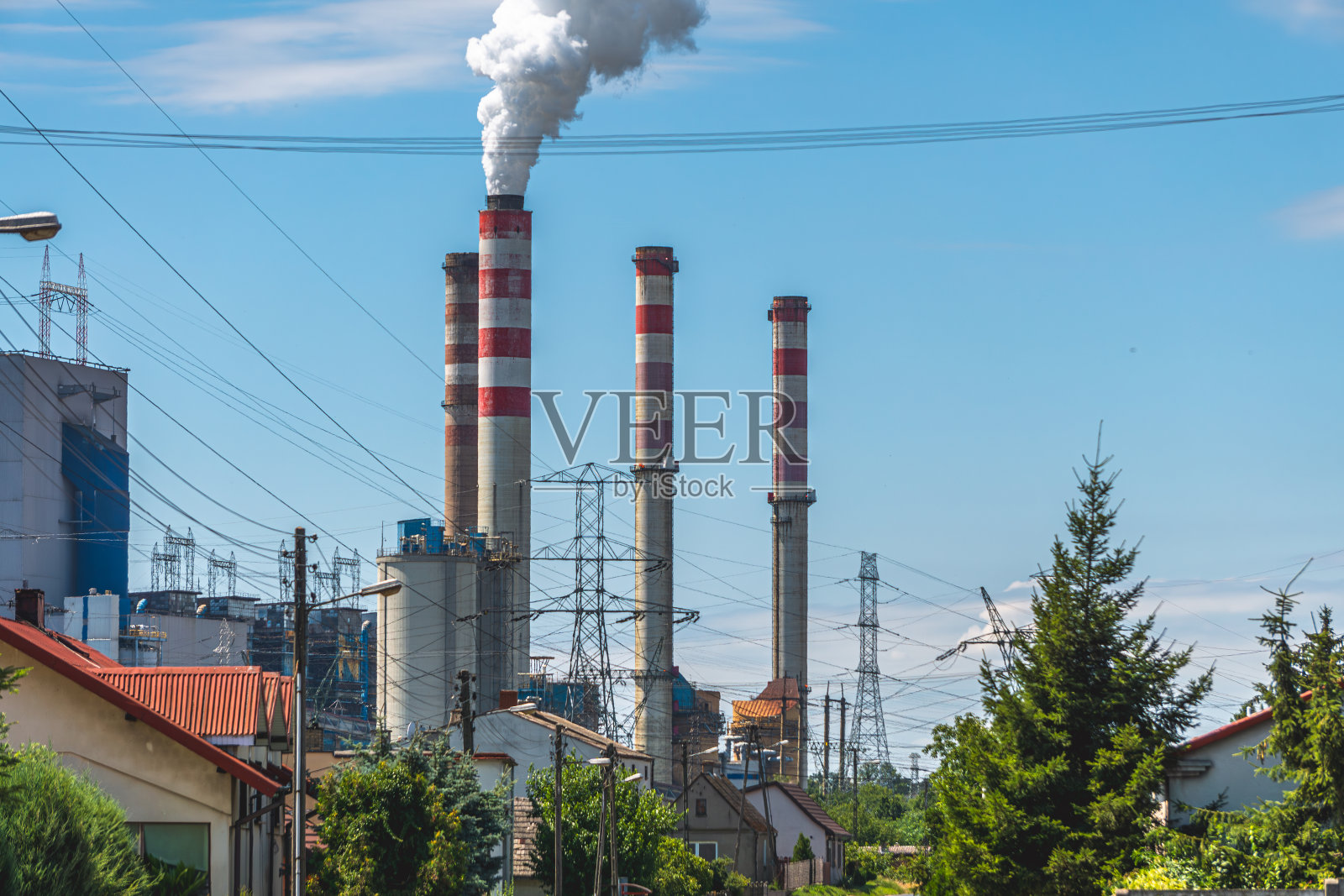 燃煤发电的非生态燃煤电厂，冒烟的烟囱，烟囱冒出的烟。城市下面的工业景观。以美丽的夏日蓝天为背景。照片摄影图片