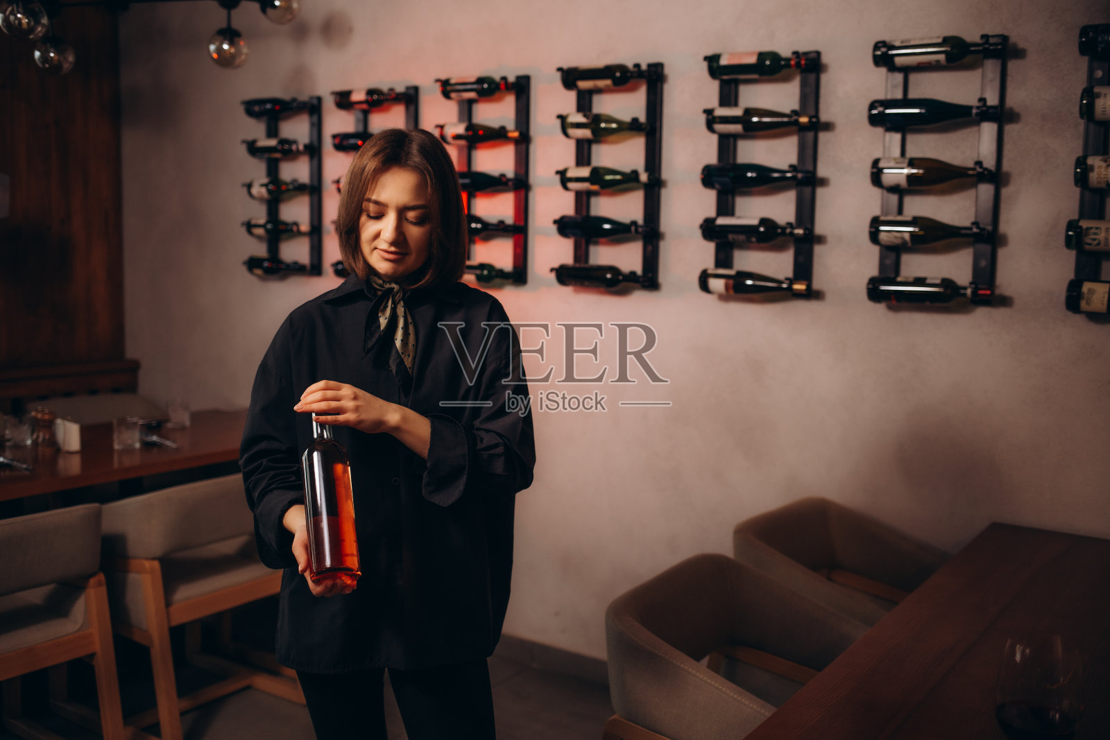 餐厅里，微笑的女侍酒师递上一个空白标签和一副眼镜的酒瓶照片摄影图片