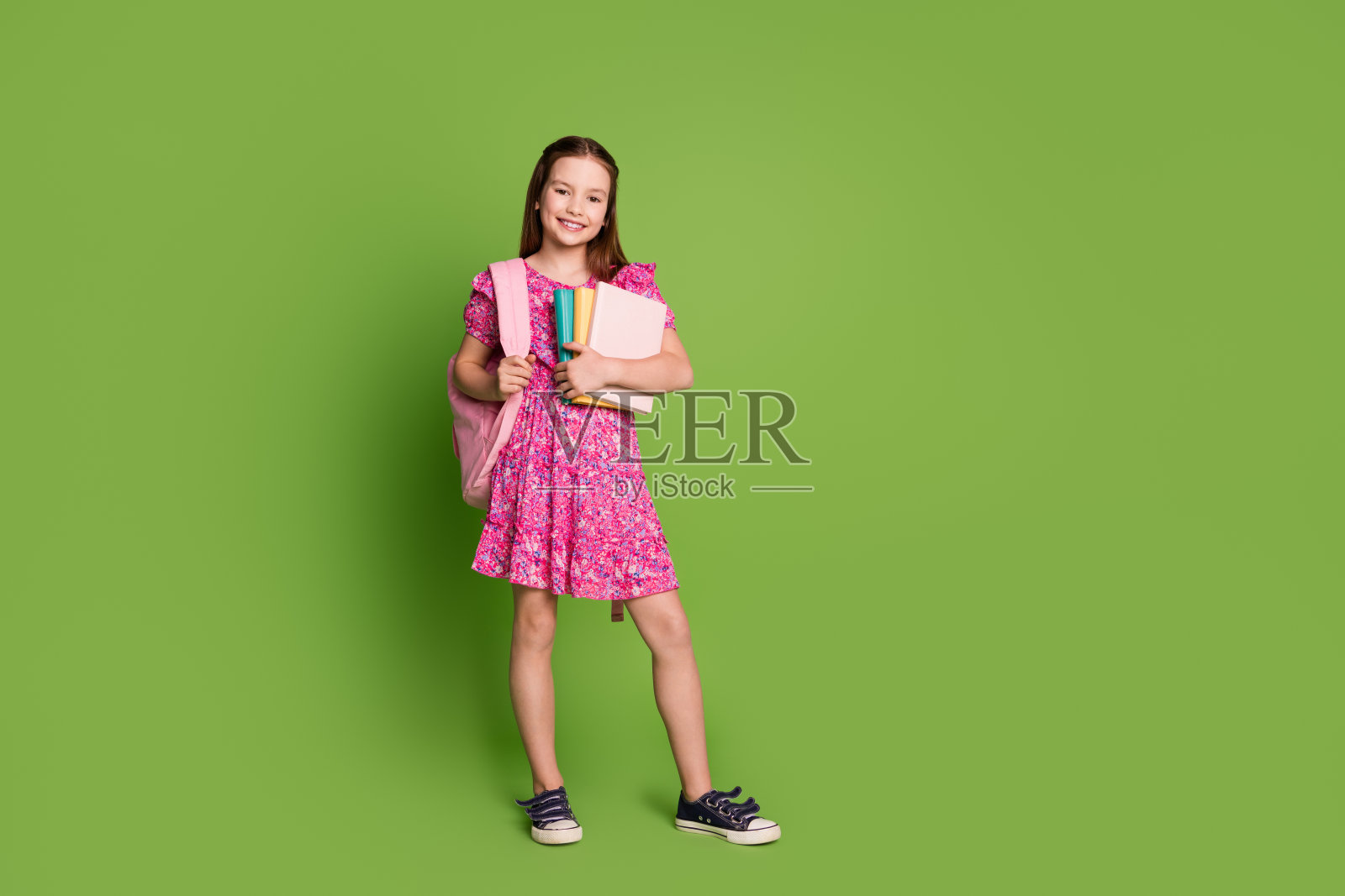 可爱的女学生的全尺寸照片背包书空的空间穿粉红色的裙子孤立的绿色背景照片摄影图片