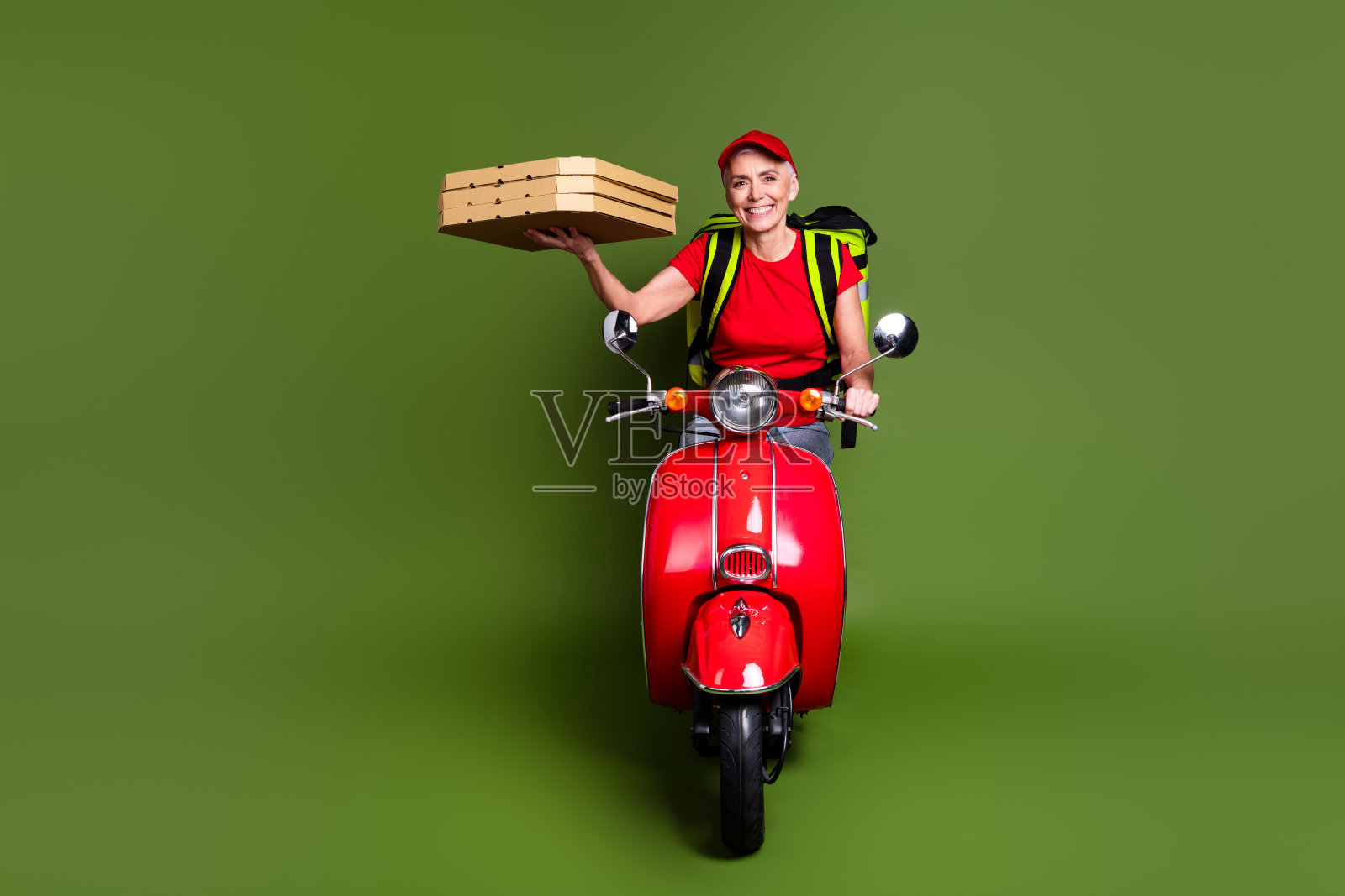 退休女士的全身照片送货服务热袋机车披萨穿着红色制服工作服隔离在卡其色背景照片摄影图片