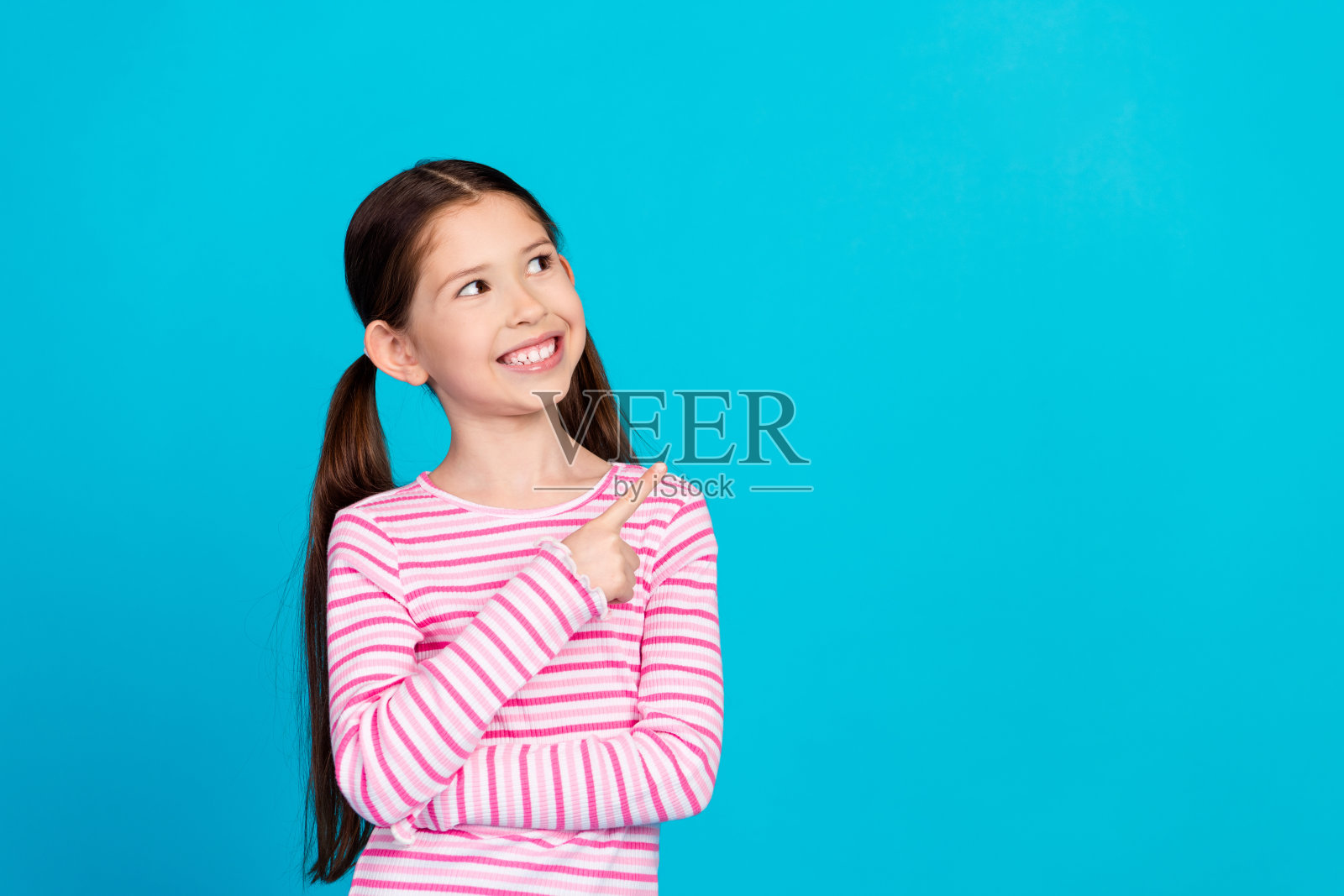 照片积极的小女孩与马尾辫穿着条纹衬衫看起来直接销售空白空间孤立的蓝色背景照片摄影图片