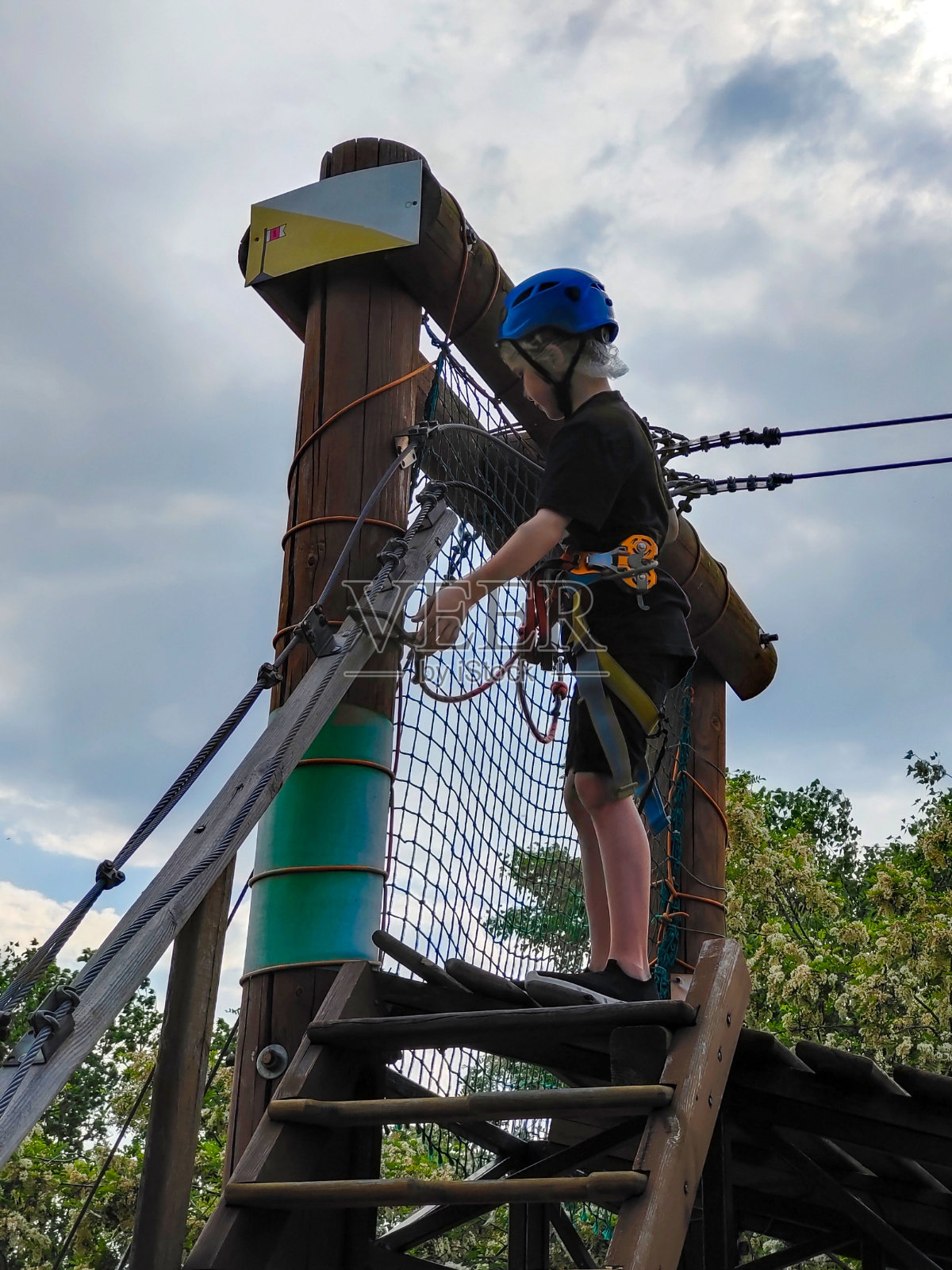 在游乐园的木制障碍跑道上，一名戴着保护装置的少年翻转保护钩照片摄影图片