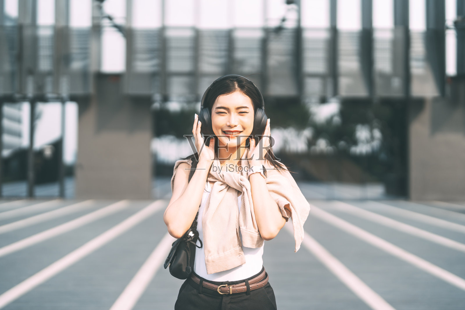 年轻的亚洲女人戴着无线耳机听音乐，十几岁的z世代的生活方式照片摄影图片