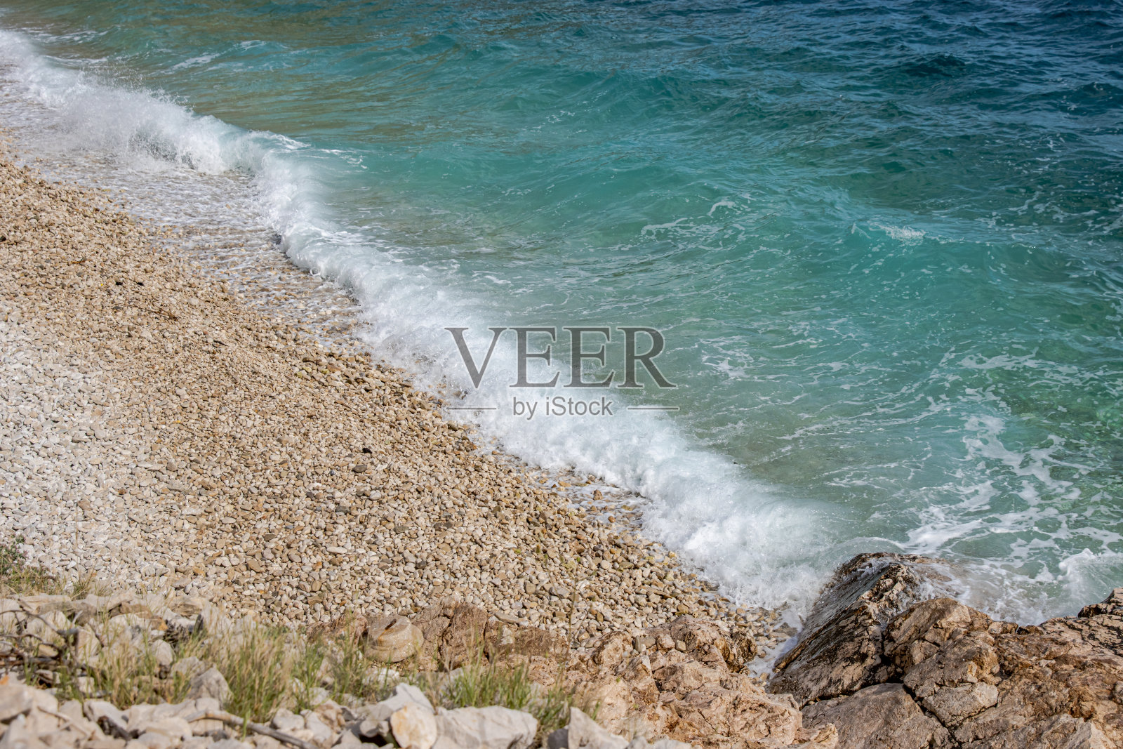 美丽的鹅卵石海滩，海浪和蓝天。轻松的鸟瞰图，暑假。假日模板横幅。海浪冲浪与惊人的蓝色海洋泻湖，海岸，海岸线。副本的空间。照片摄影图片