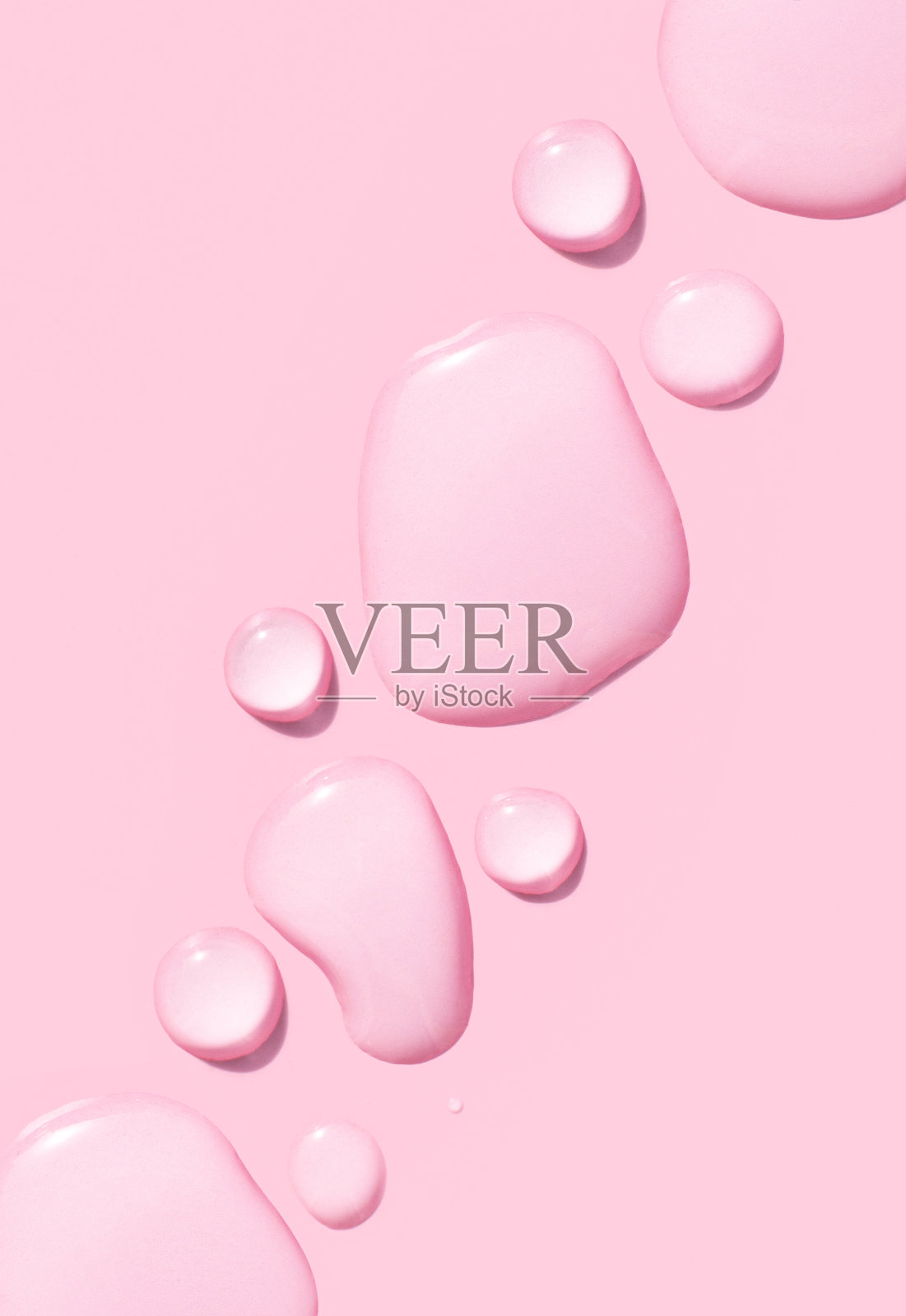 粉红色背景上的透明凝胶血清圆滴照片摄影图片