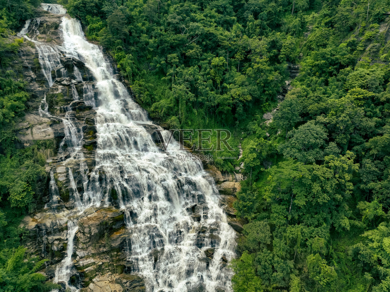 鸟瞰泰国清迈茵他侬国家公园郁郁葱葱的热带绿色森林中的瀑布。这个自然景观展示了水的可持续性和风景优美的旅游目的地。照片摄影图片