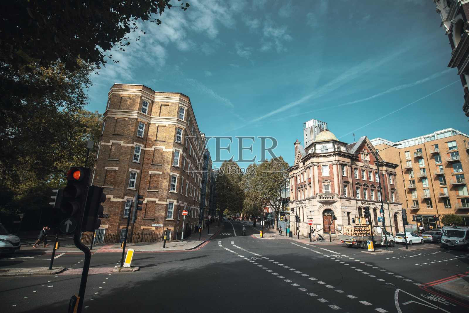伦敦的一个十字路口，有红绿灯、行人和汽车，以砖房为特色，混合了古老和现代的建筑风格。照片摄影图片