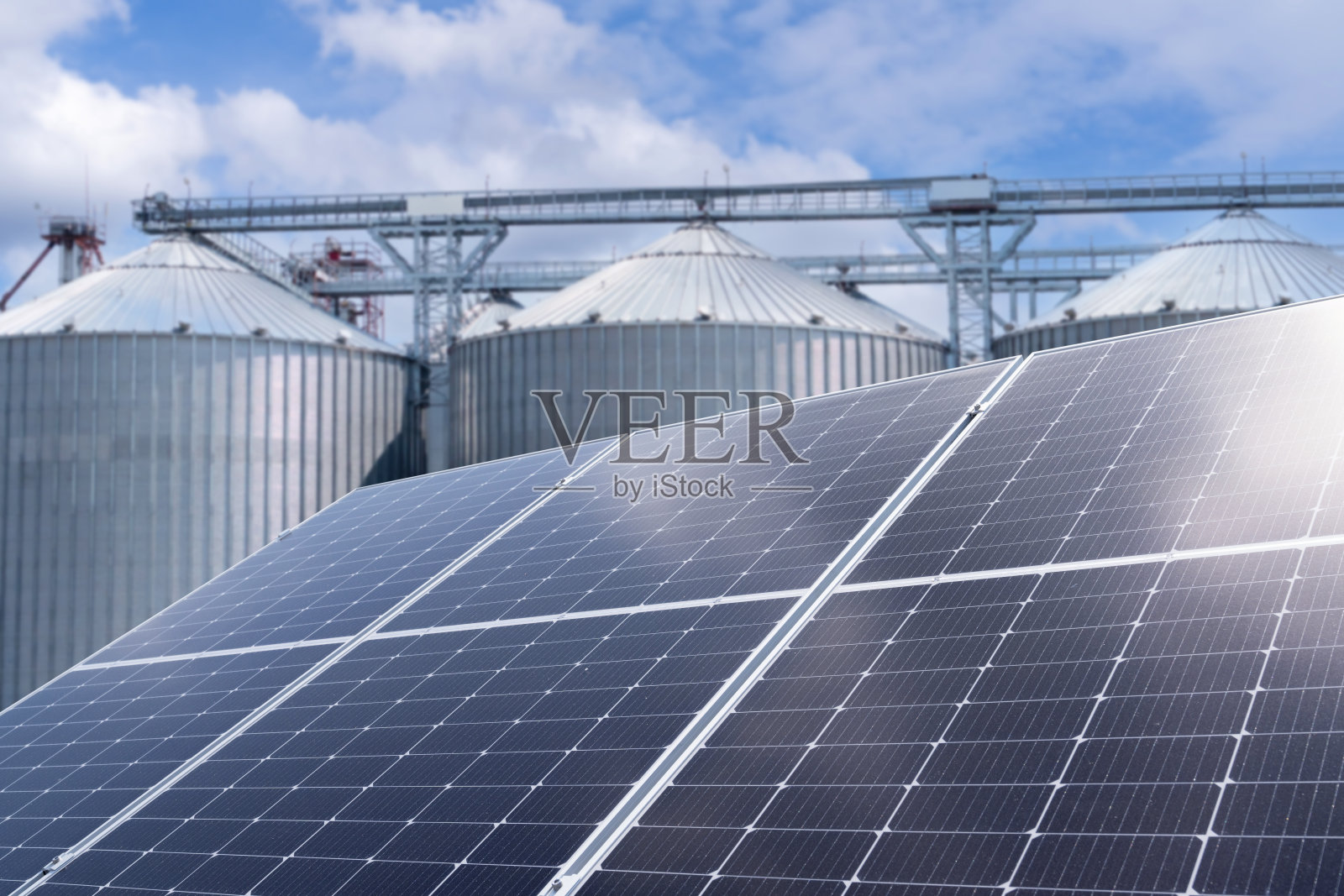 使用可再生能源的现代农场。背景是带有筒仓的太阳能电池板照片摄影图片