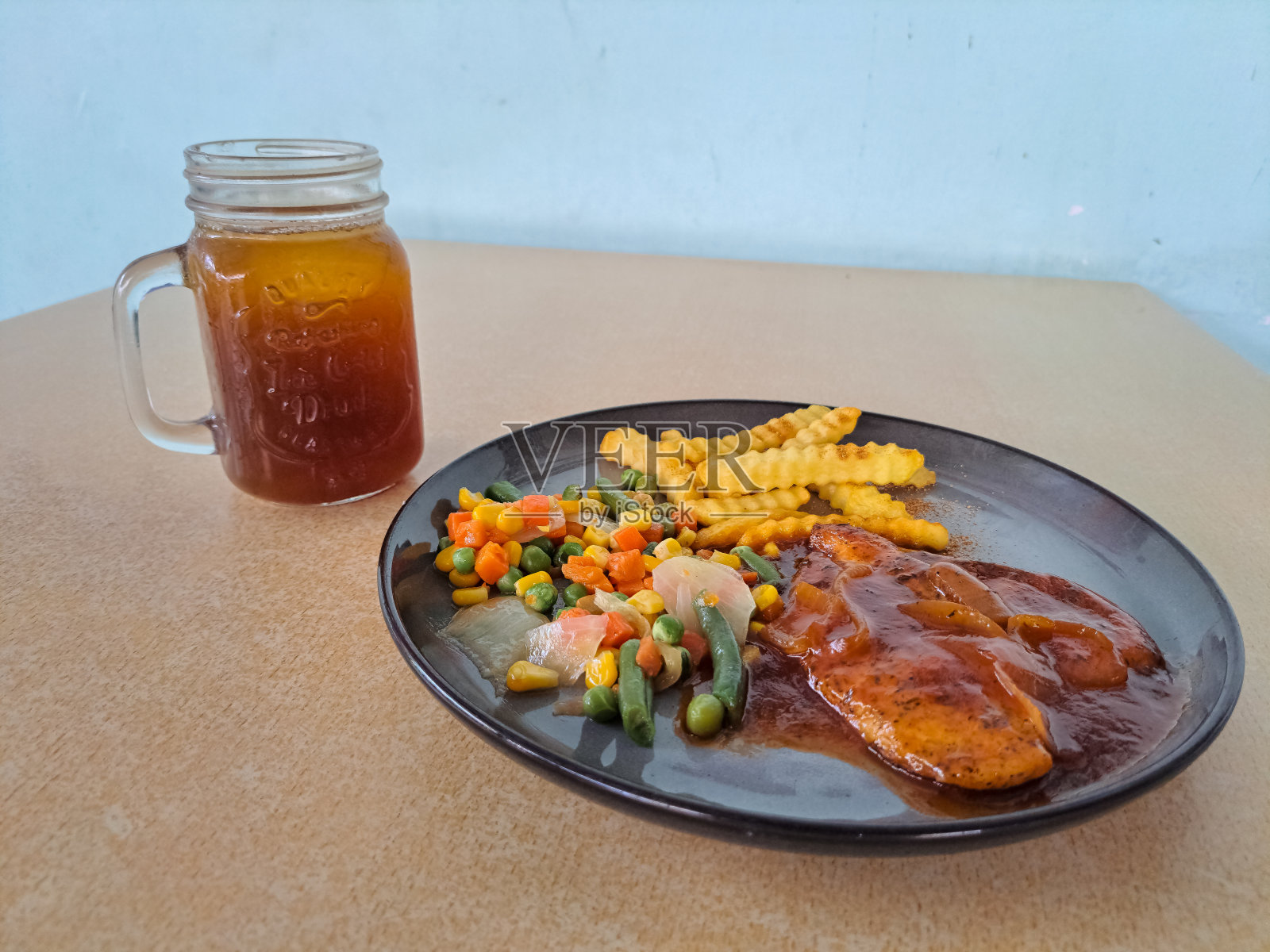 美味的烟熏烤鸡，烤鸡胸，烧烤酱，薯条和混合蔬菜。新鲜的茶冰在杯子里。食物和饮料菜单。照片摄影图片