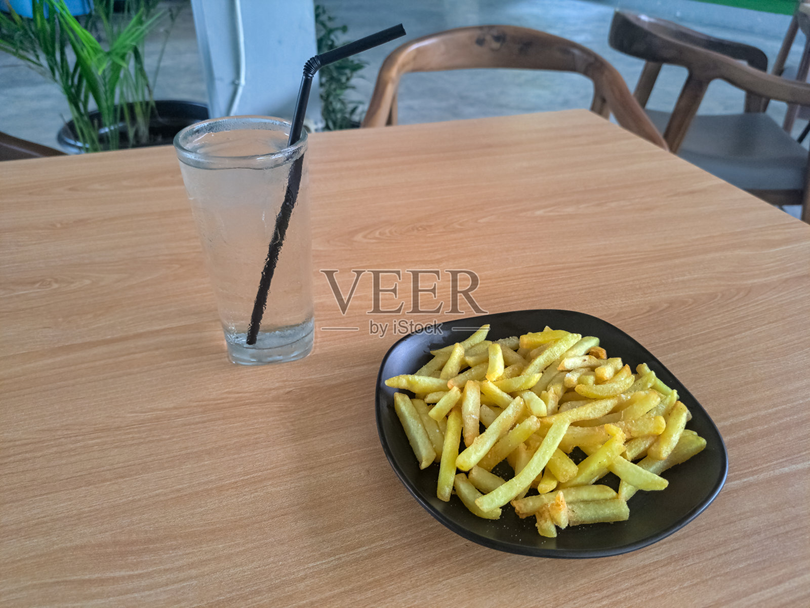 盘子里有美味的炸薯条，杯子里有冰凉的冰矿泉水。食物和饮料菜单。照片摄影图片