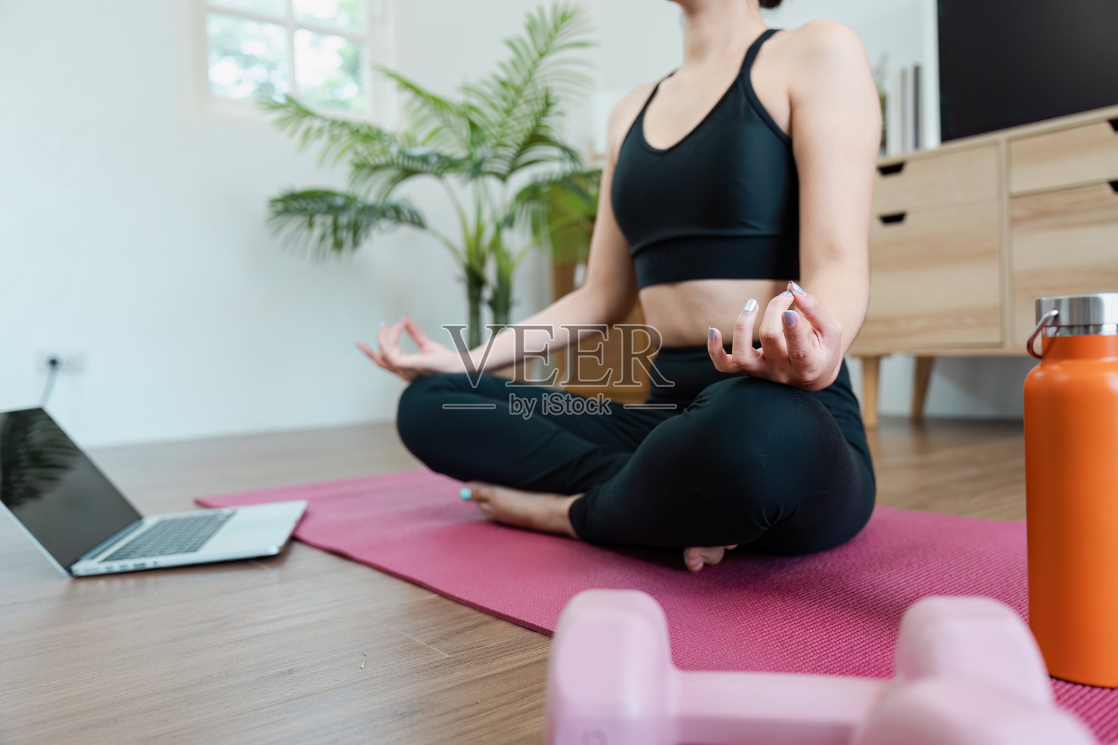 女士在家练习瑜伽，在现代客厅用笔记本电脑和运动器材健身照片摄影图片
