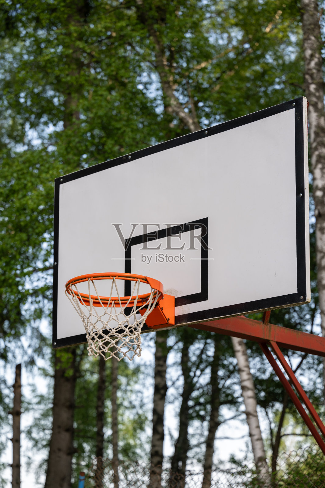 带篮子的新篮球板。靠近篮筐，板或篮。阳光明媚的日子里篮筐网的特写。篮筐在橙色底部视图在一个白色的背景。照片摄影图片