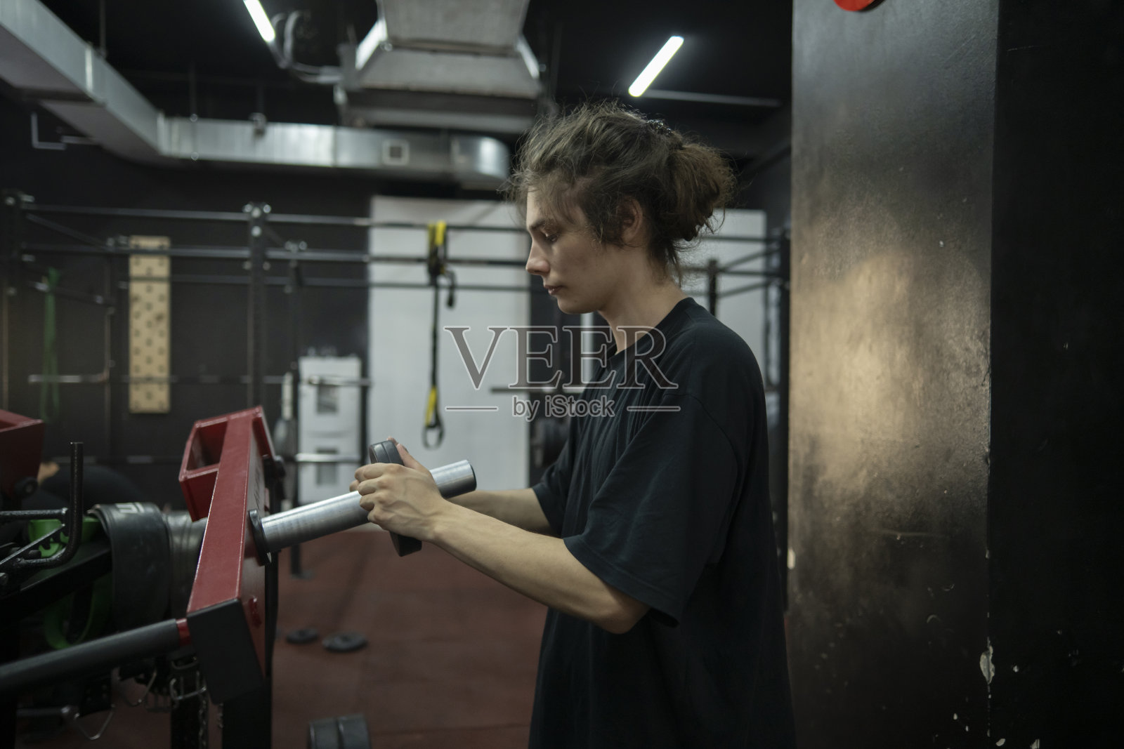 一名身穿黑色t恤的男子在健身房调整举重器械照片摄影图片