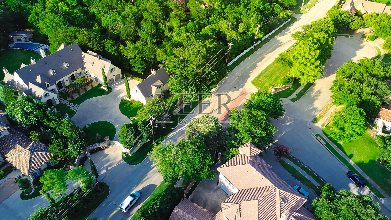葱郁的绿树环绕着昂贵的郊区豪宅，带有混凝土屋顶瓦片，游泳池，大后院，达拉斯沃斯堡郊区精心修剪的景观，鸟瞰图照片摄影图片