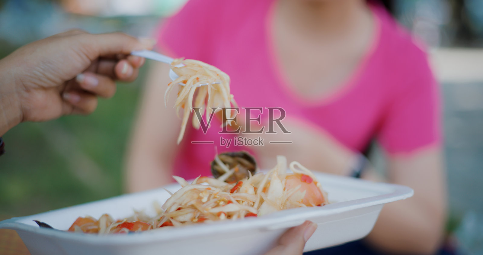 两个年轻女子坐在公园里吃东西。照片摄影图片