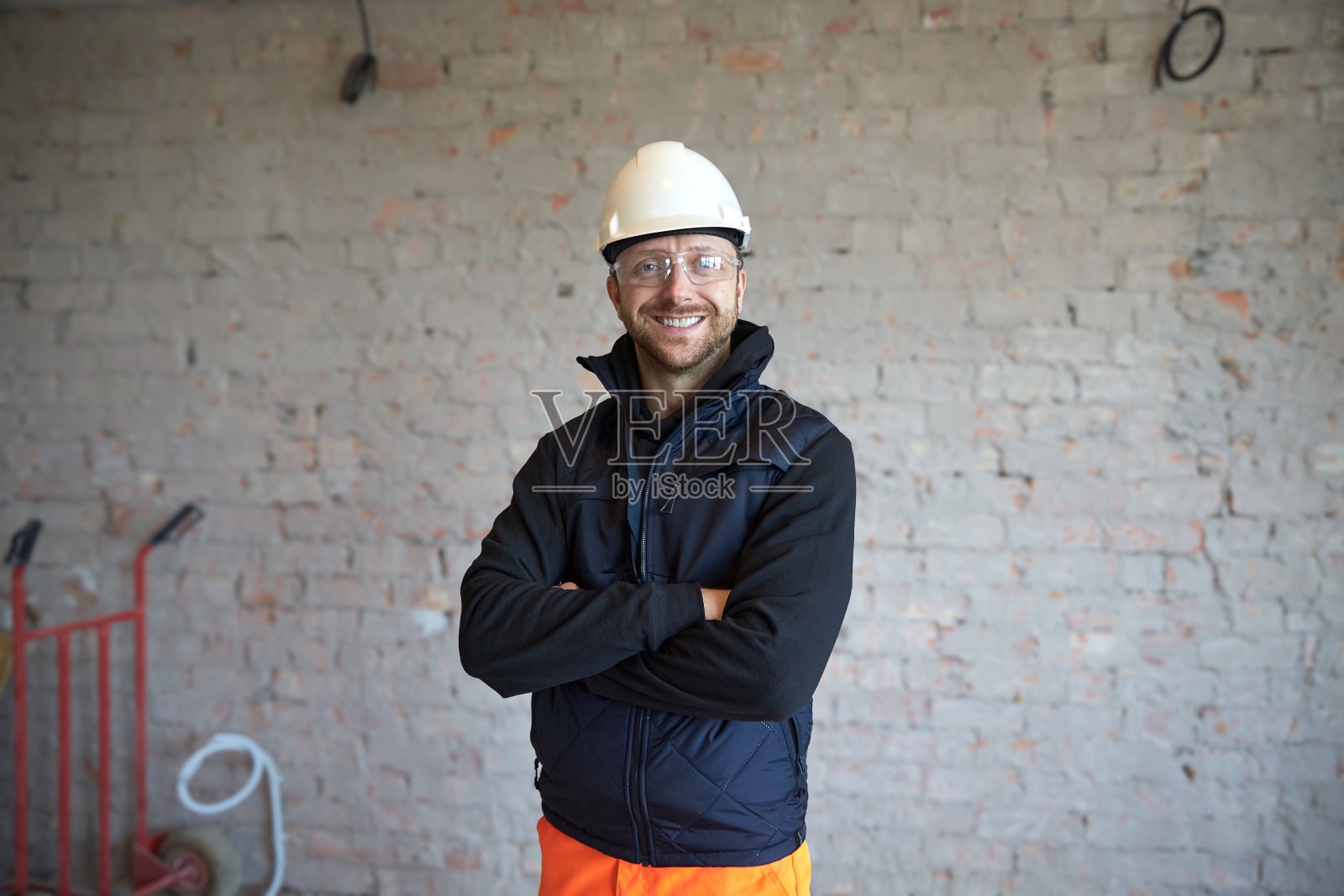 一个微笑的年轻人站在建筑工地的肖像。照片摄影图片