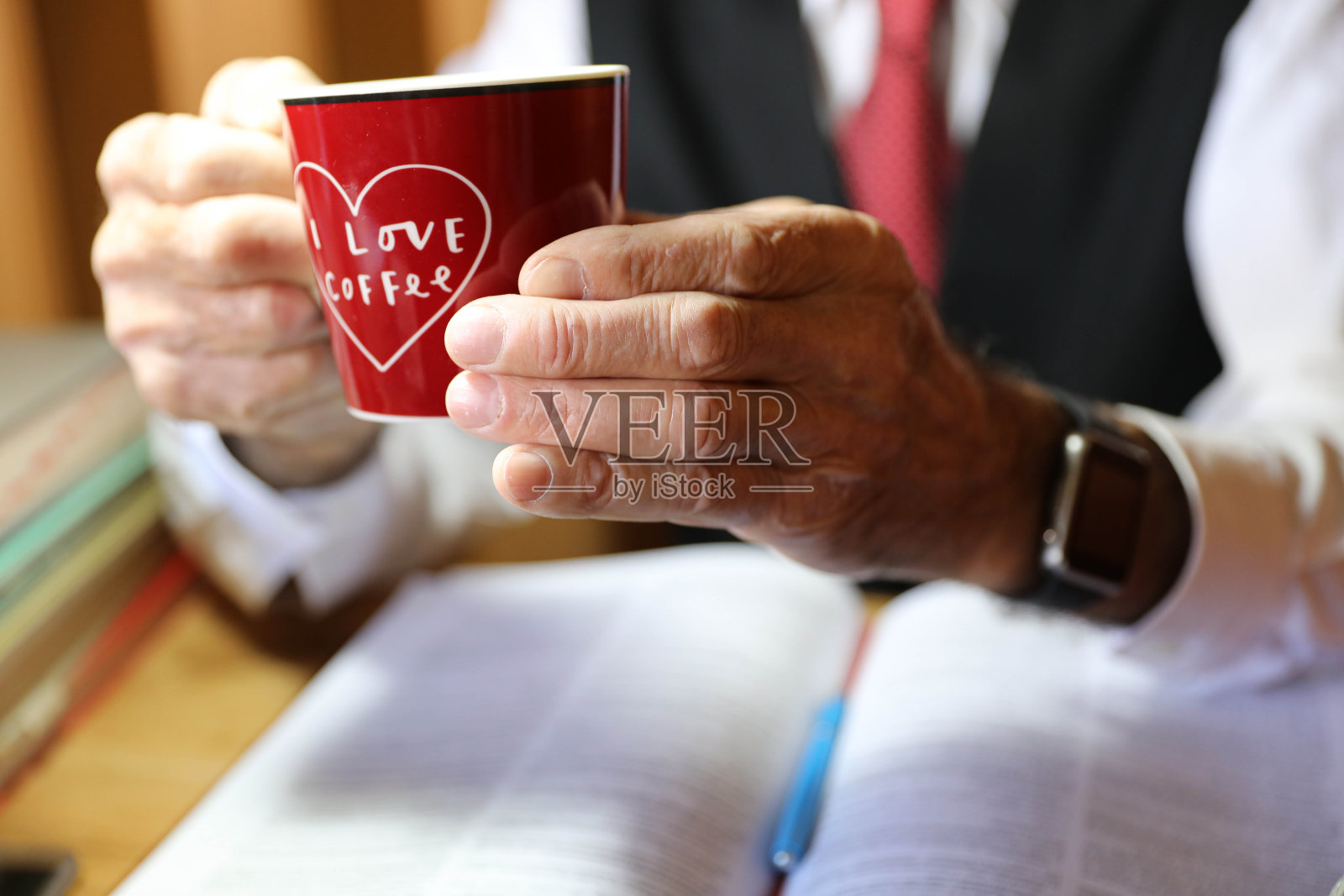 一位老人在办公室里端着一杯咖啡照片摄影图片