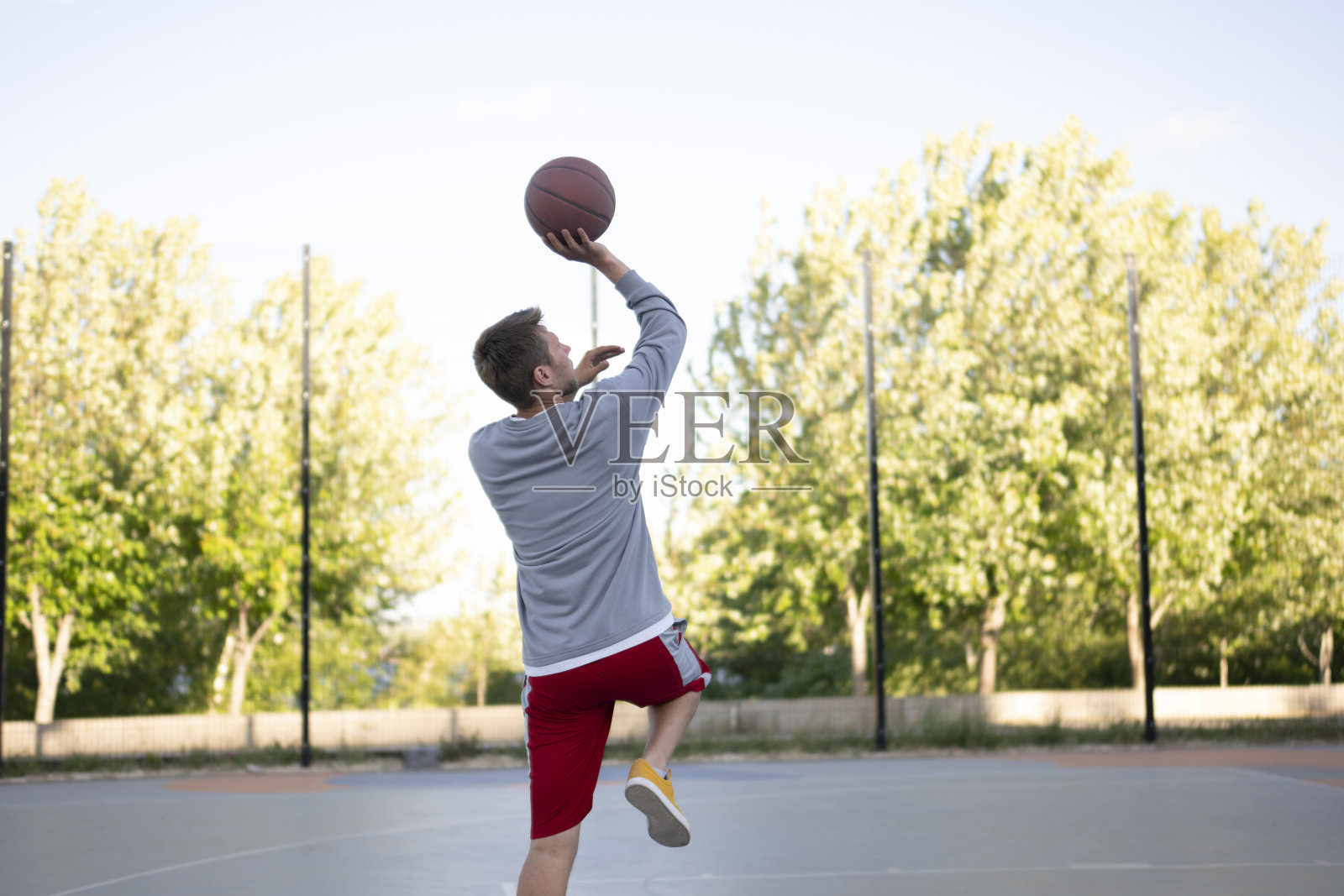 一名专心致志的年轻人在户外进行篮球训练，运球和投篮练习照片摄影图片