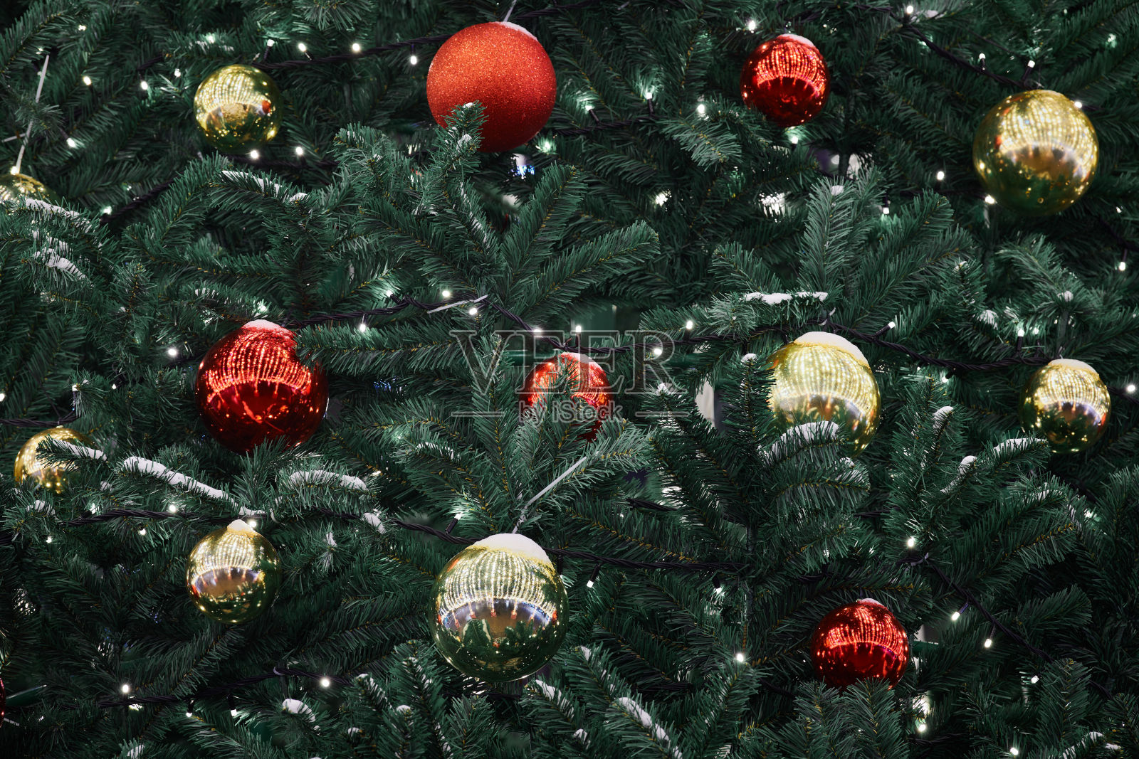 喜庆的新年圣诞树上装饰着红黄色的圣诞球和花环灯照片摄影图片