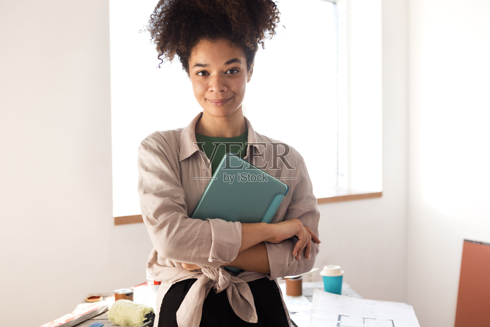 迷人的微笑的非洲妇女拿着平板电脑和咖啡，检查房屋平面图照片摄影图片