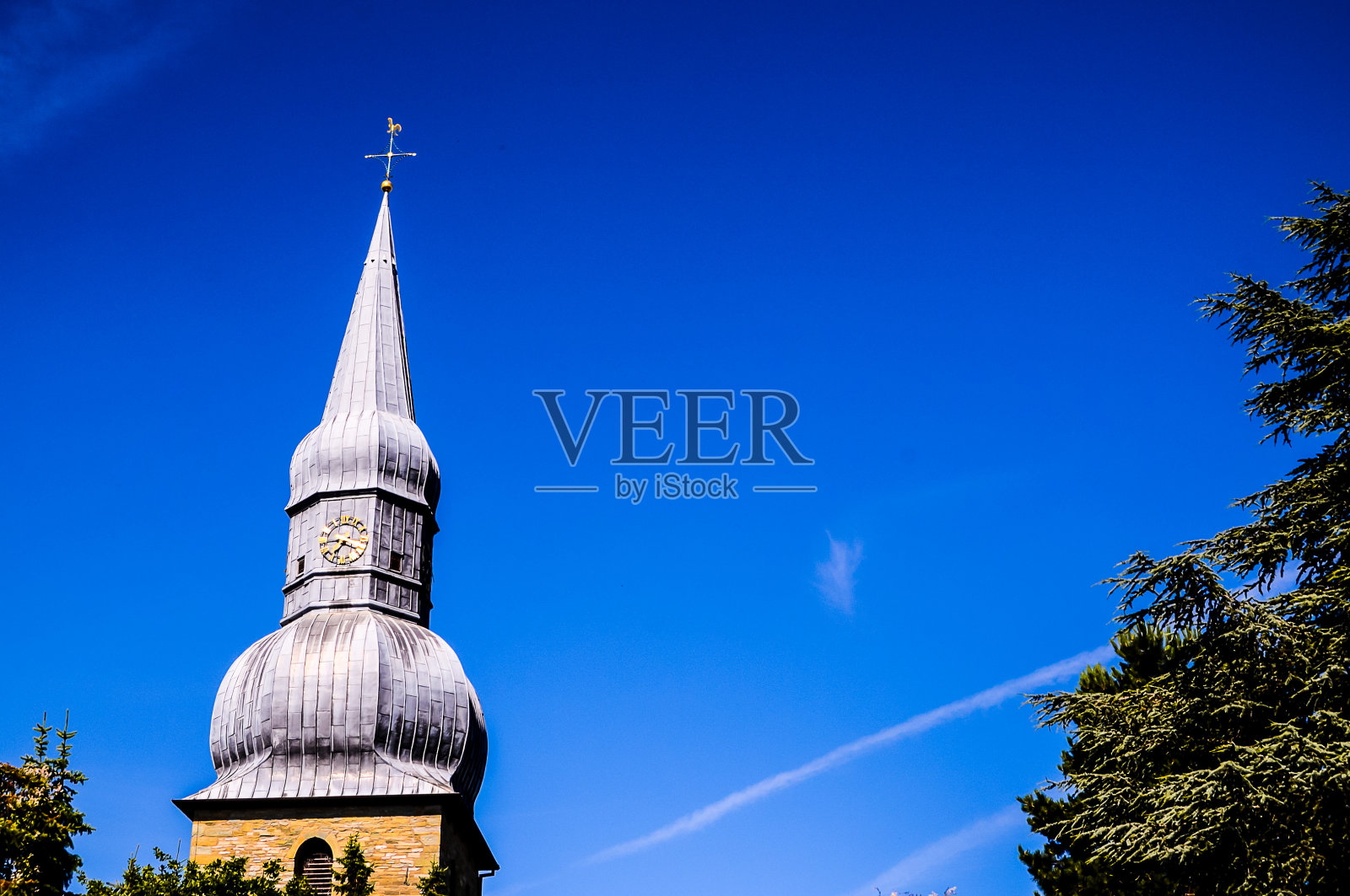 钟塔教堂的尖顶高塔，前面有一个钟照片摄影图片