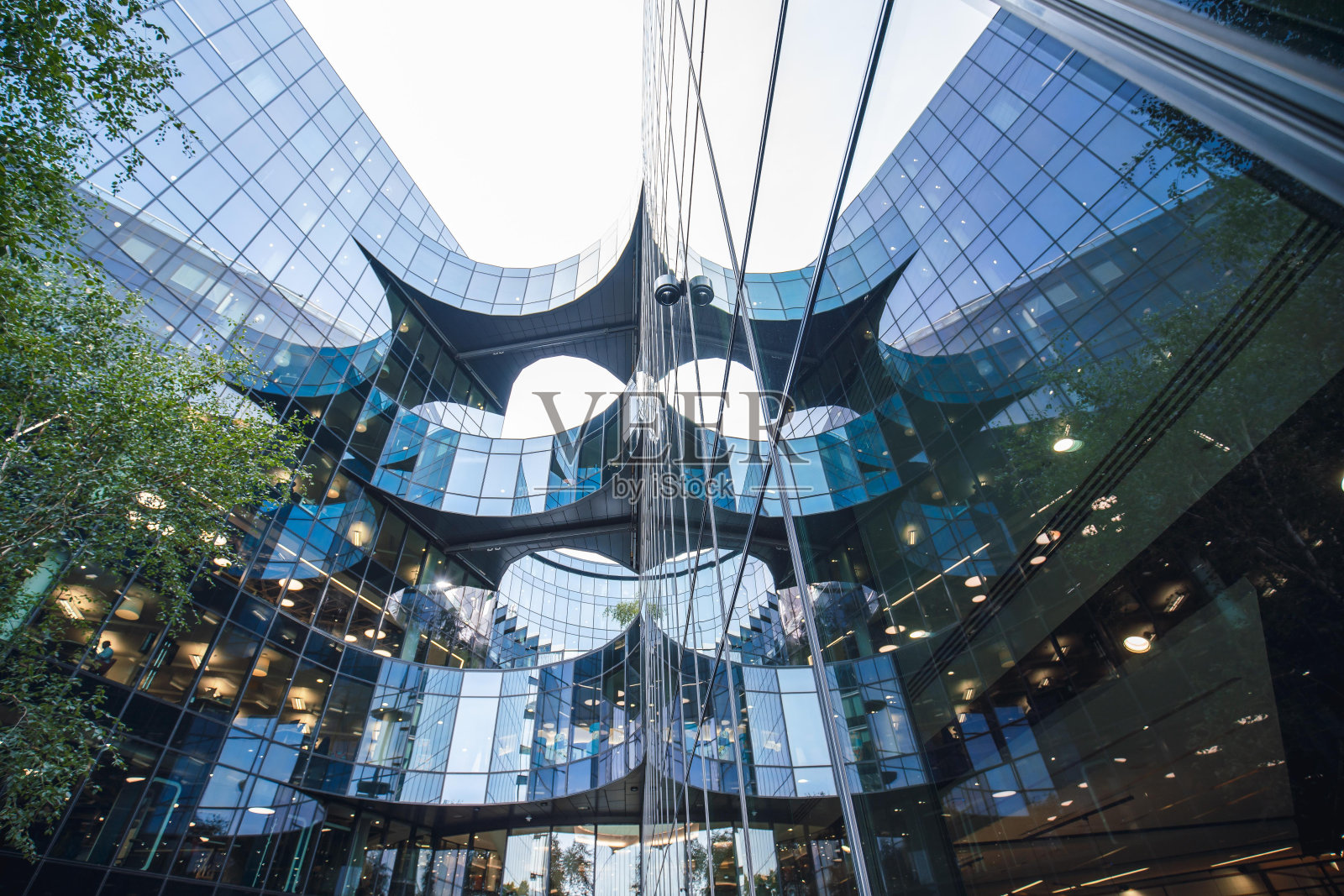 英国伦敦一座玻璃幕墙的现代办公大楼的低角度视图。该建筑有独特的弧形设计，大窗户反映了周围的城市景观。照片摄影图片