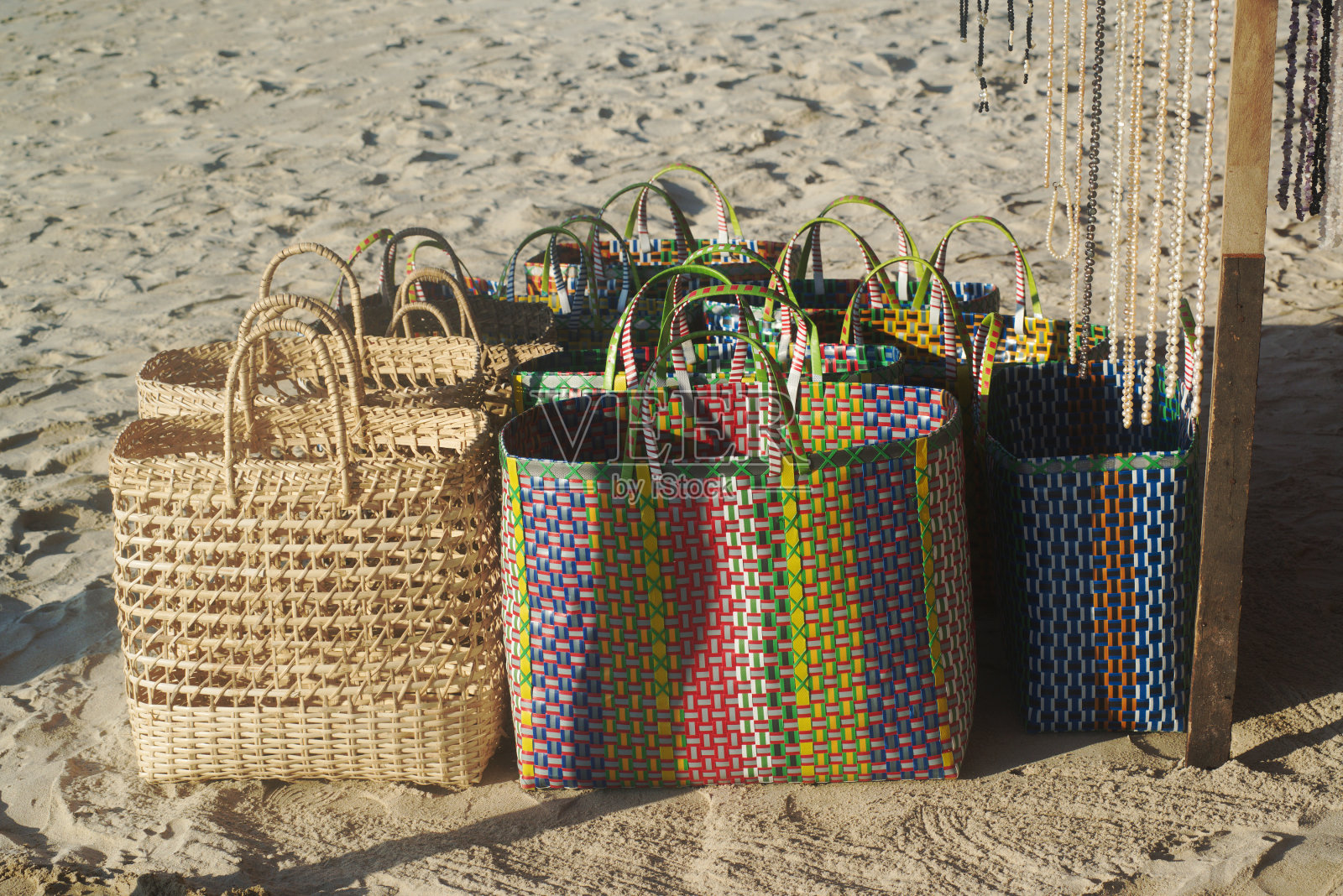 手工编织的椰子和塑料篮子在海滩上出售。照片摄影图片