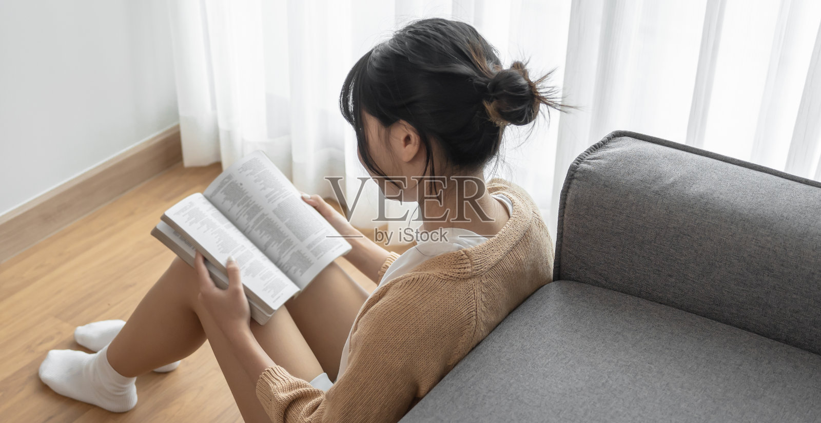 亚洲女性阅读书籍，在家里放松，在打开的书前感到舒适照片摄影图片