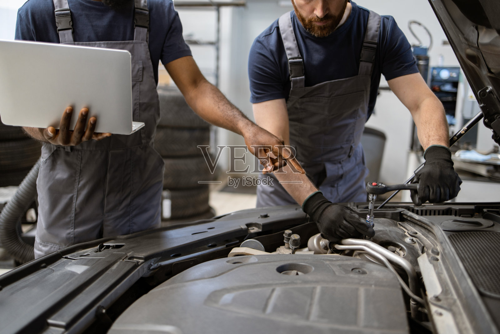 机械师在车间使用笔记本电脑进行汽车发动机的维修照片摄影图片