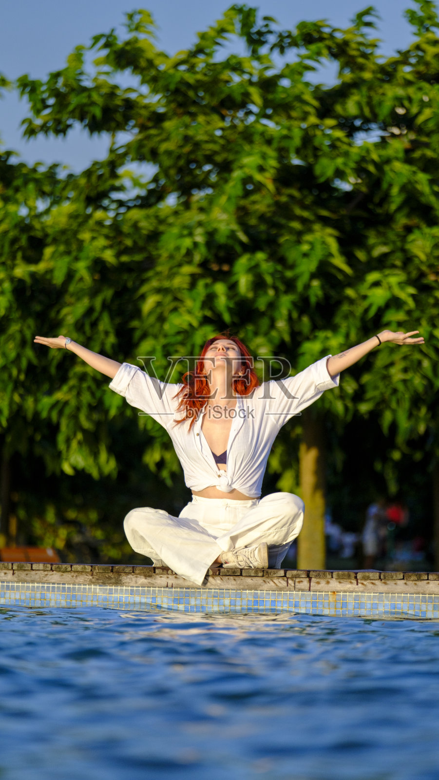 一个年轻漂亮的红发女人在泳池边冥想照片摄影图片