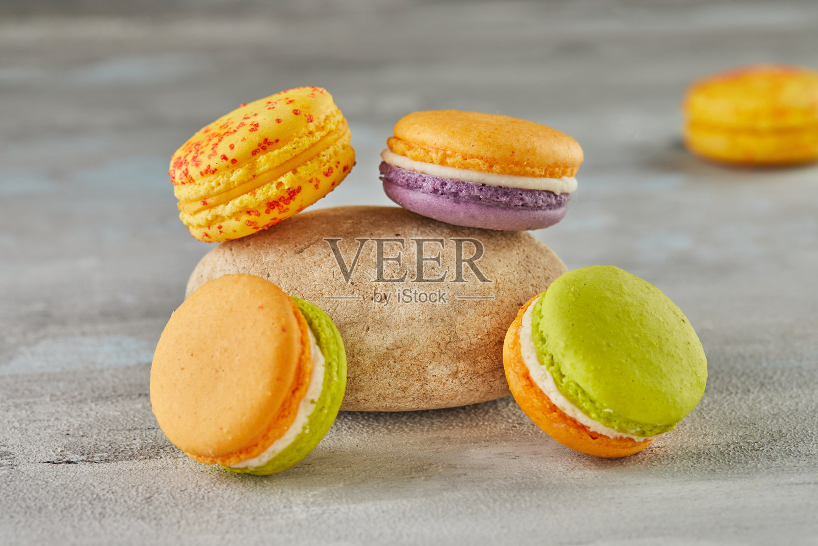 混凝土背景上的彩色马卡龙与石头照片摄影图片