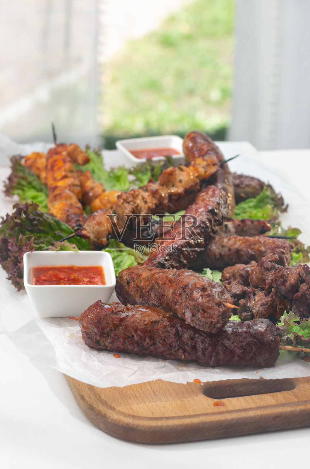 用烤肉串、肉片做成的菜。烤鸡、牛肉、猪肉配烧烤酱照片摄影图片