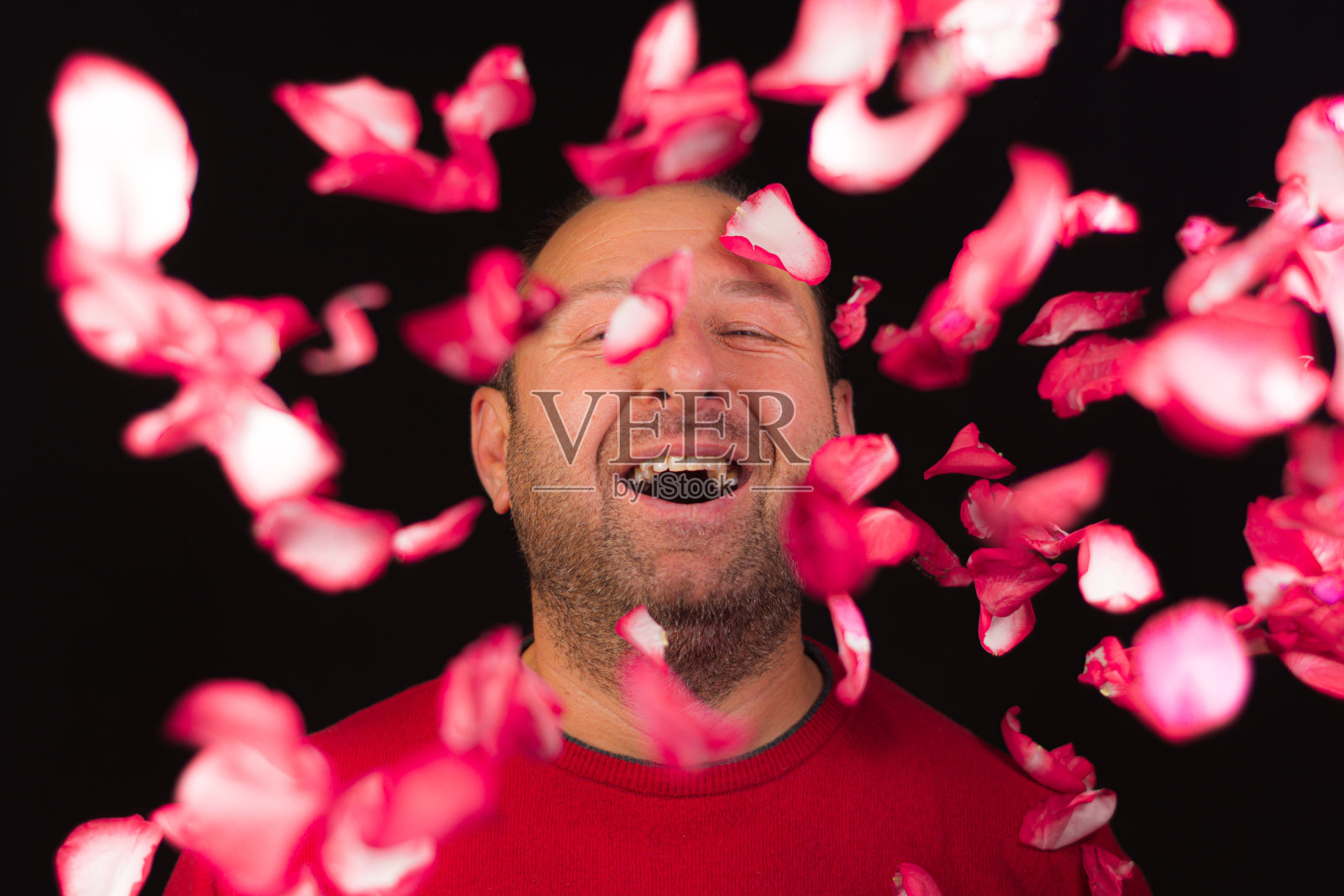 男人在玫瑰花瓣间微笑照片摄影图片