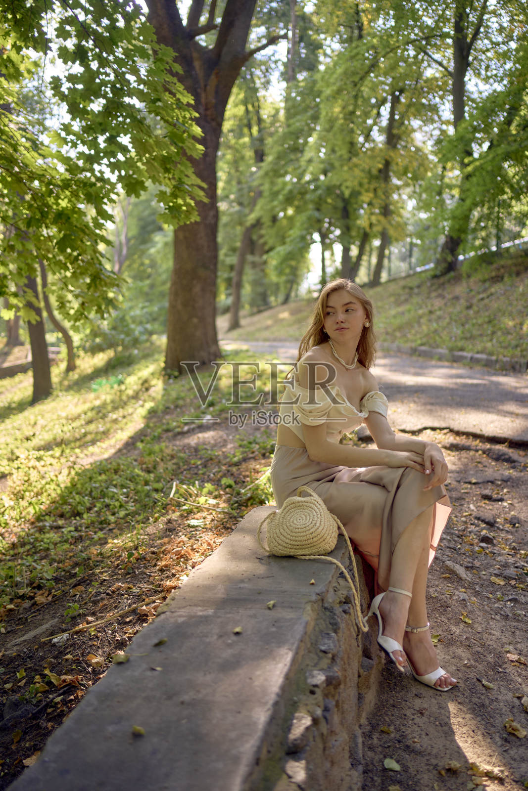 一个漂亮的十几岁的女孩，穿着丝绸裙和紧身胸衣，在公园里和河边散步照片摄影图片