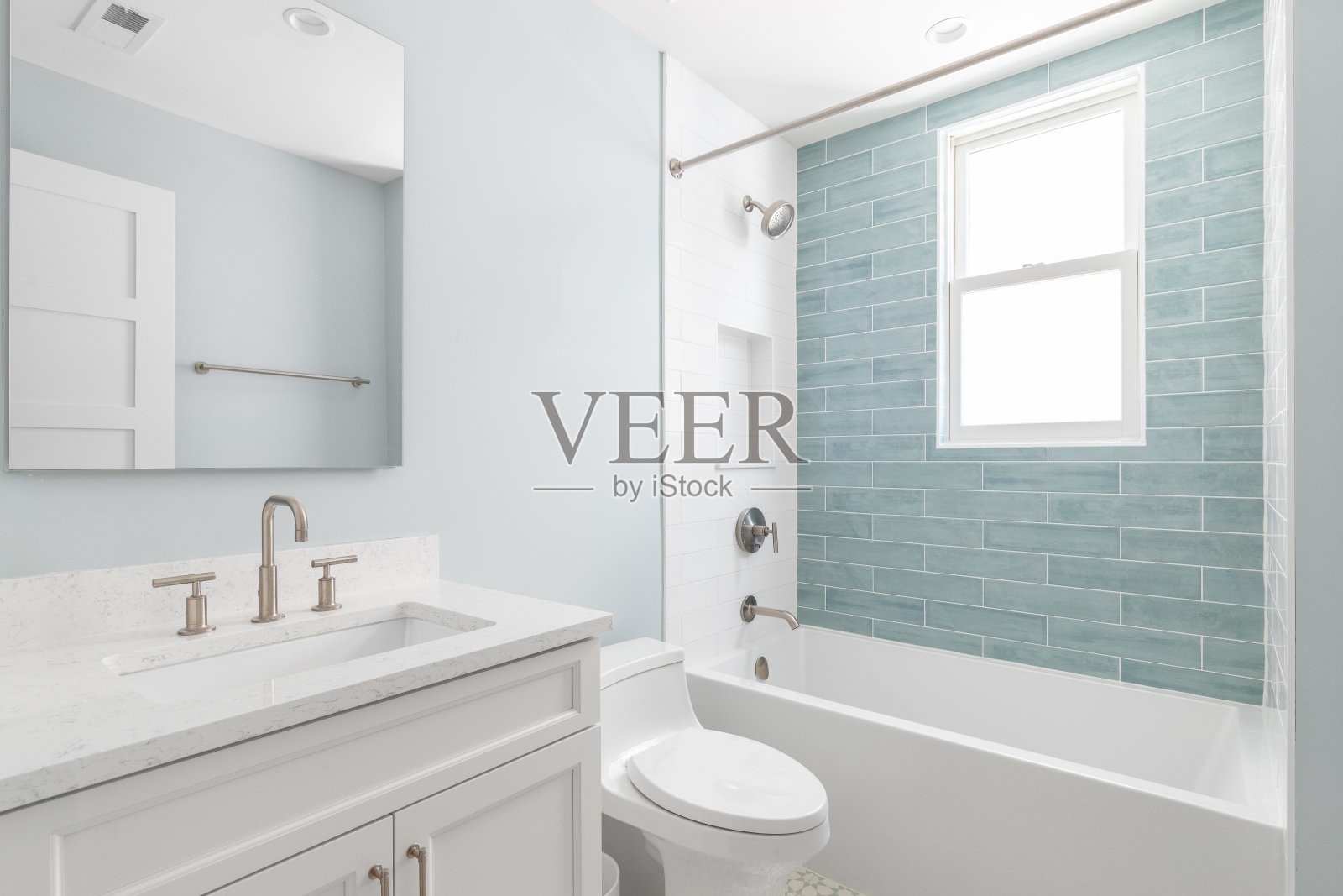 浴室里有一个白色的橱柜和白色和蓝色的地铁瓷砖淋浴。照片摄影图片