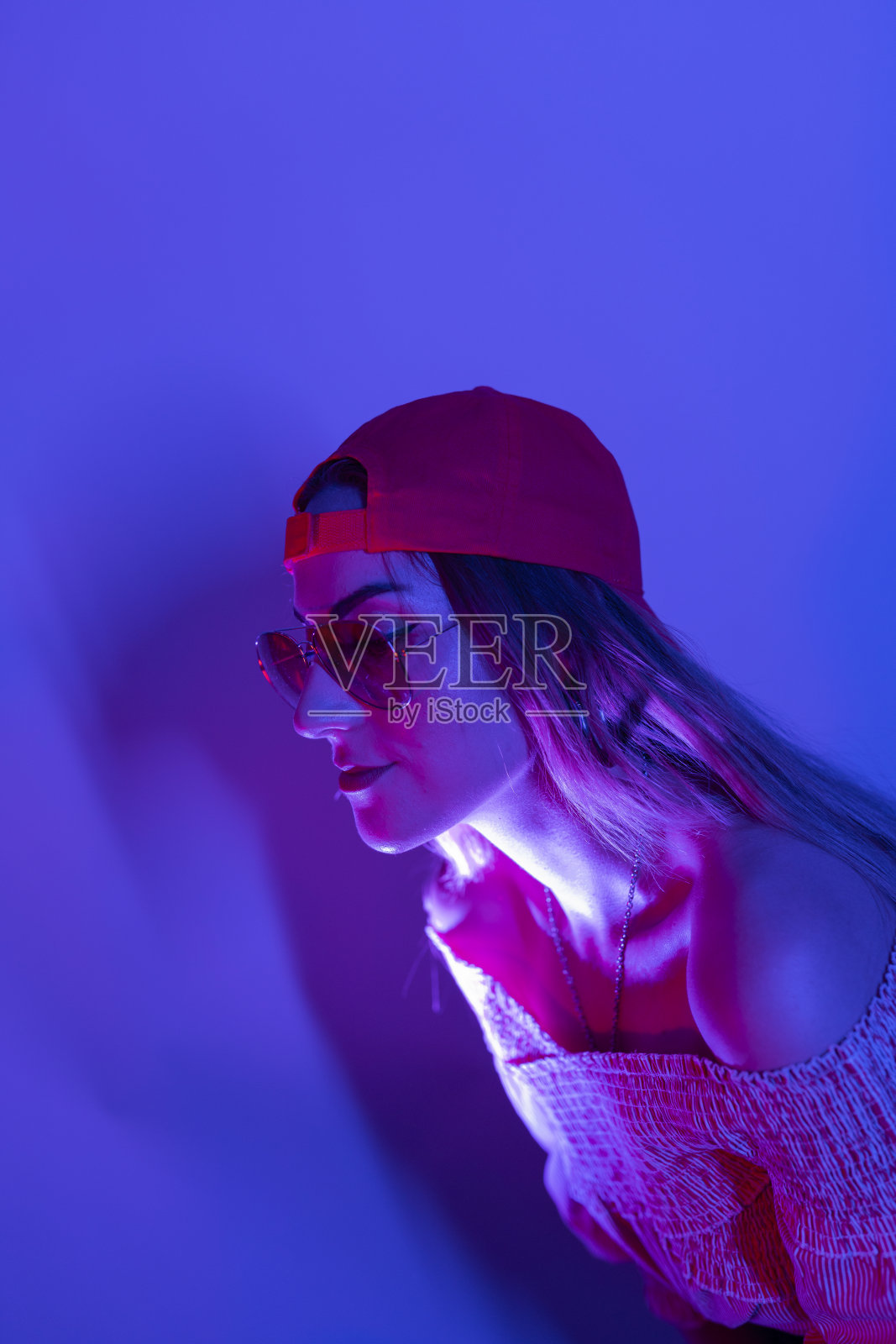 高级时装模特在彩色明亮的霓虹灯蓝色和紫色在工作室摆姿势。美丽女人的肖像与时尚发光的化妆。照片摄影图片