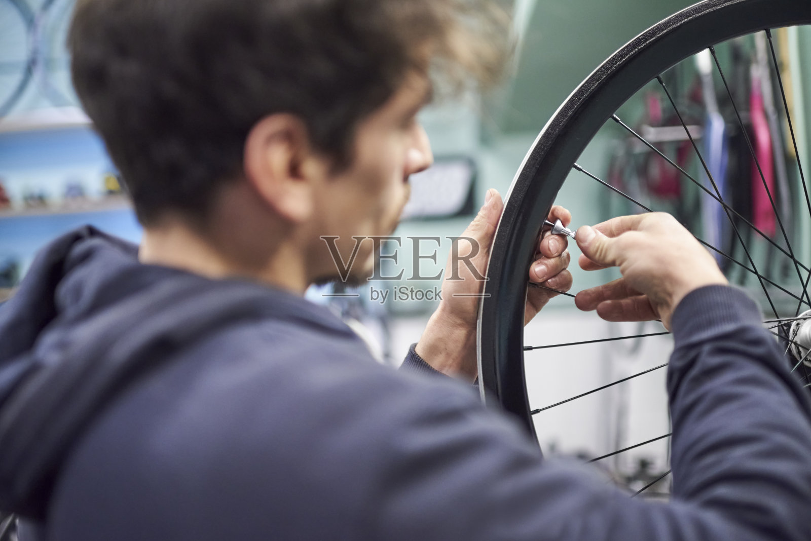 在自行车车间里，一名男子正在用扳手拧紧自行车轮辐照片摄影图片