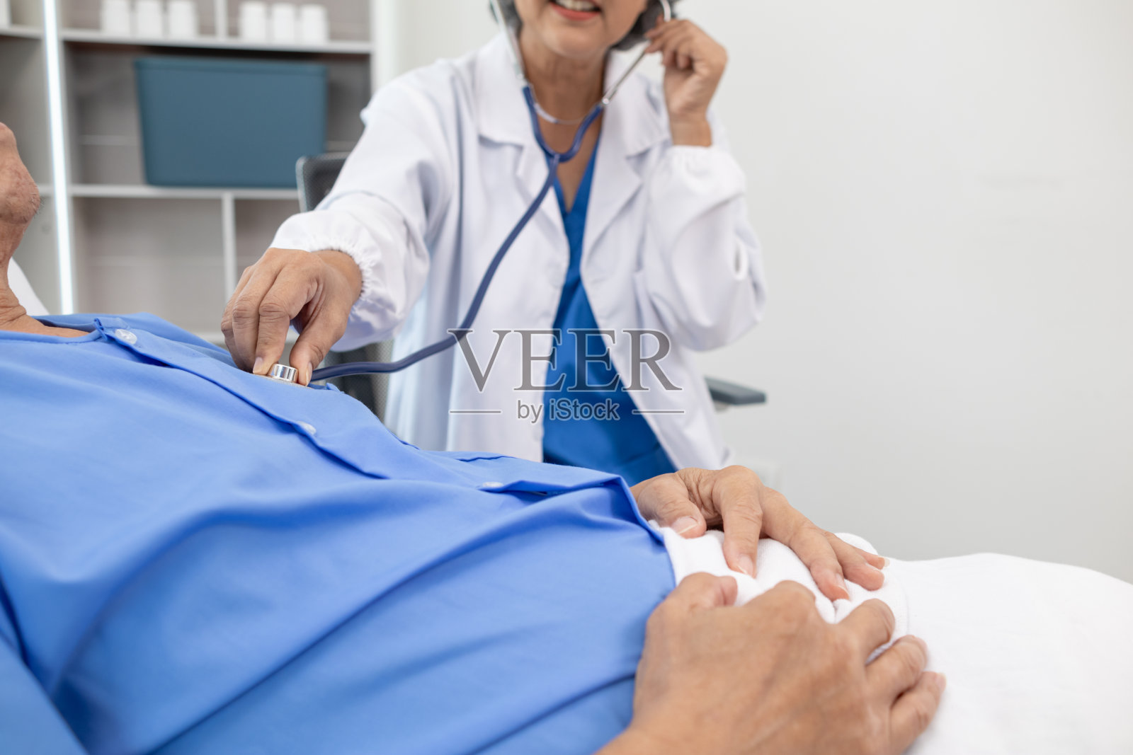 医生用听诊器听病人的心跳来发现心脏病的毛病。医生用听诊器听病人的心率来收集信息，诊断疾病并提供治疗。照片摄影图片