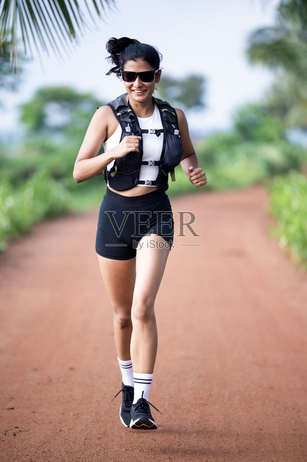 一个漂亮的运动女人穿着运动服在公园里跑步。训练日照片摄影图片