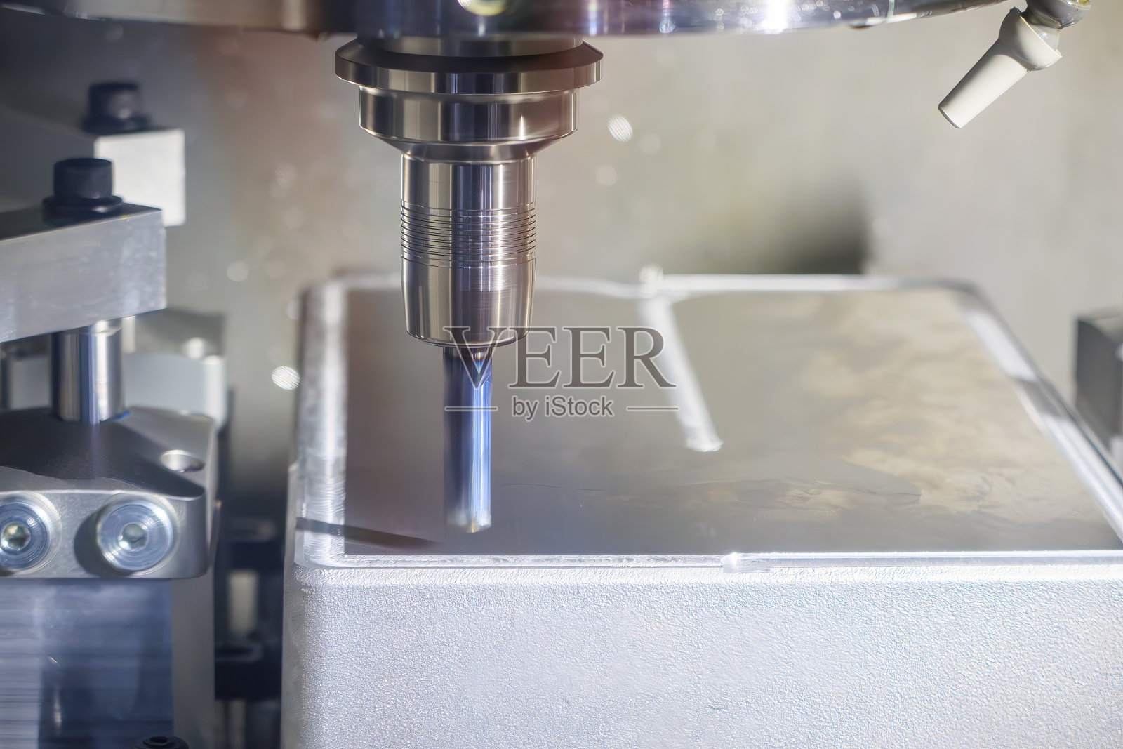 浅蓝色场景中，数控铣床用平面立铣刀切割模具零件。照片摄影图片