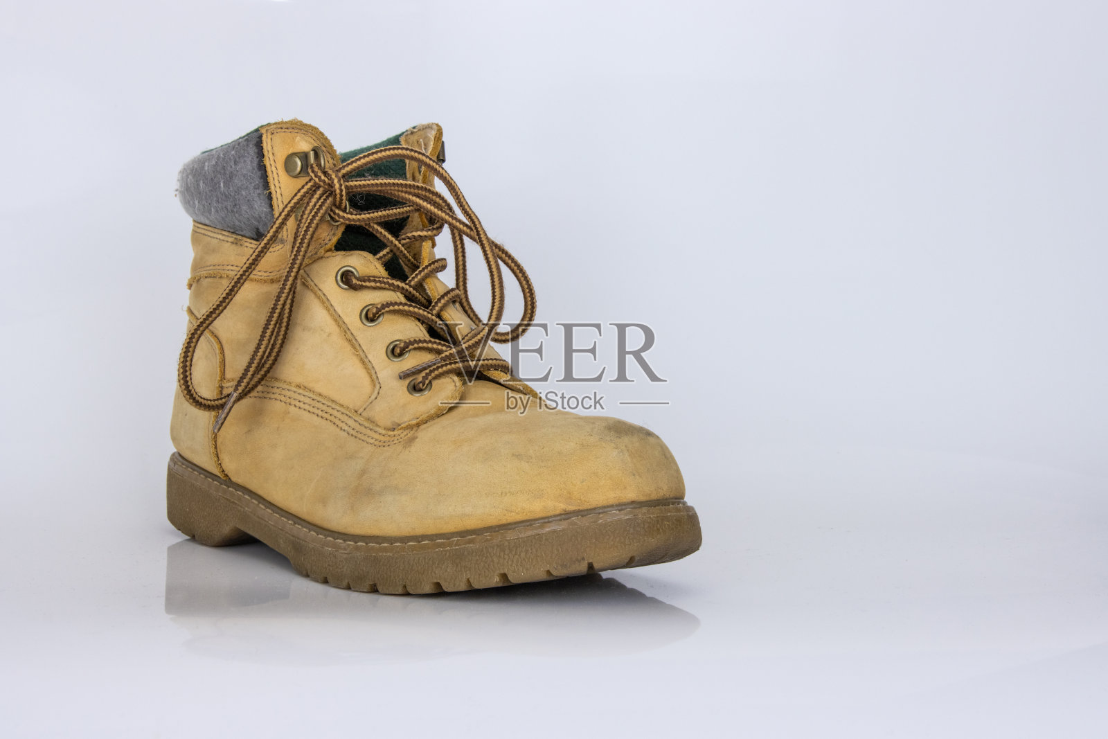 一双旧的黄色徒步旅行蕾丝靴，隔离在白色光滑的表面上，具有美丽的反射效果。二手旅游步行鞋。侧视图。副本的空间。白色背景。照片摄影图片