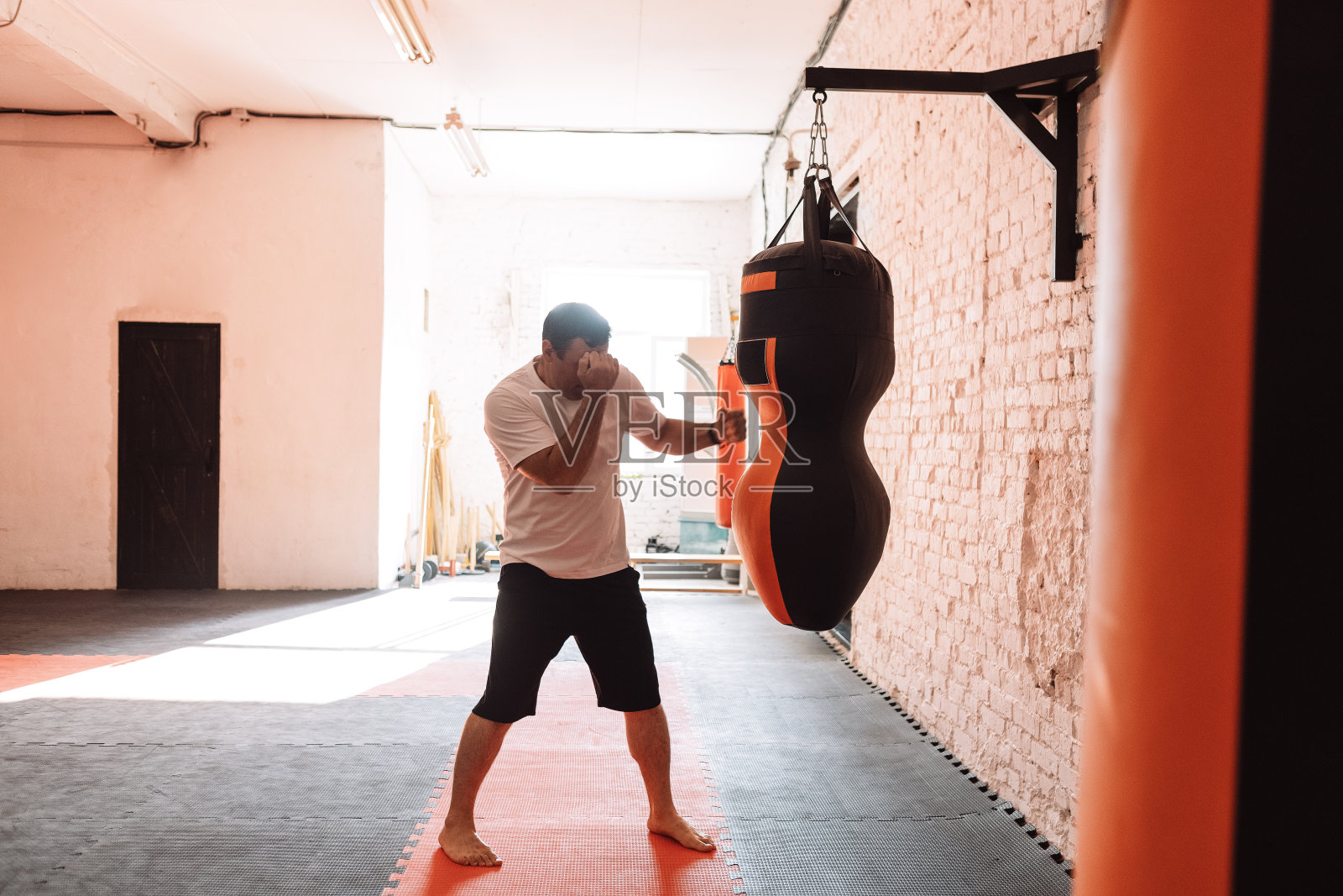 成熟的男人在健身房打沙袋照片摄影图片