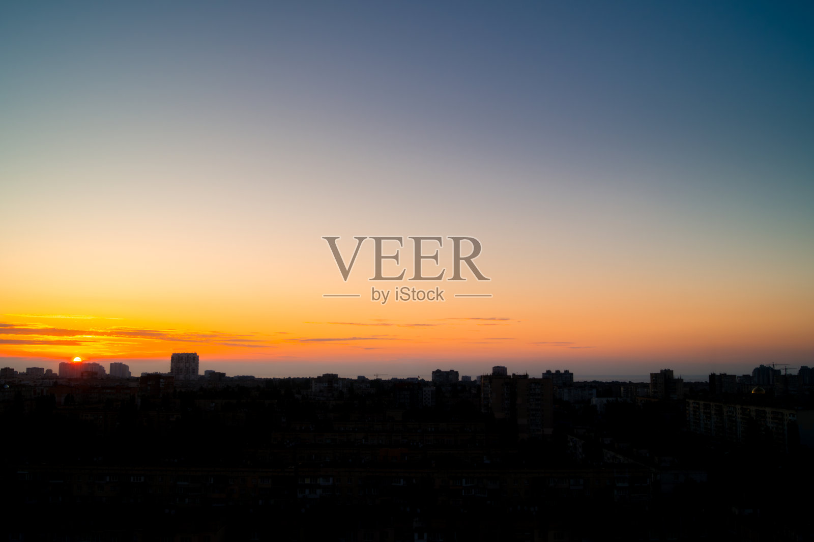 城市上空晴空升起的太阳的一半照片摄影图片